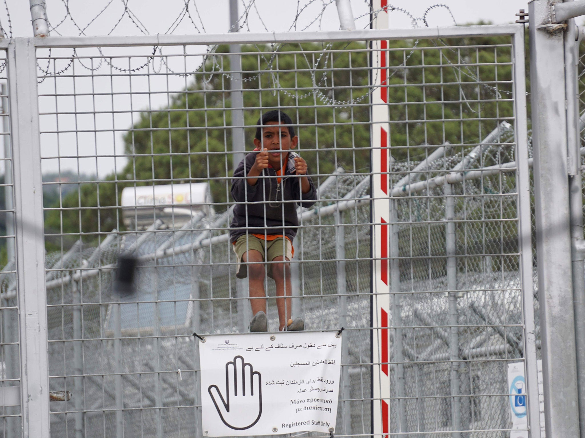 A child looks through the fence at the Moria detention camp for migrants and refugees at the island of Lesbos on May 24, 2016.