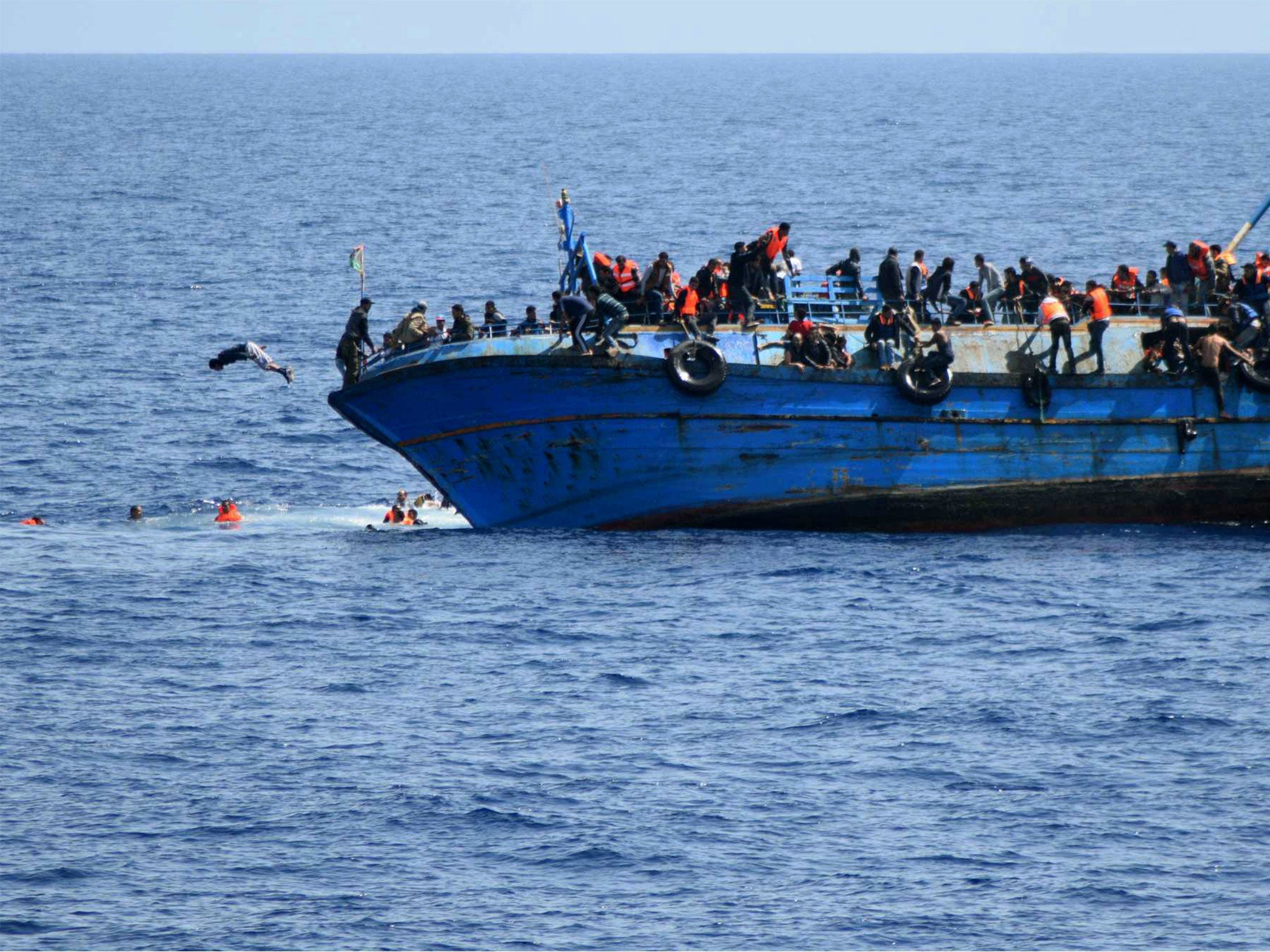 People jump out of a boat before it overturns off the Libyan coast