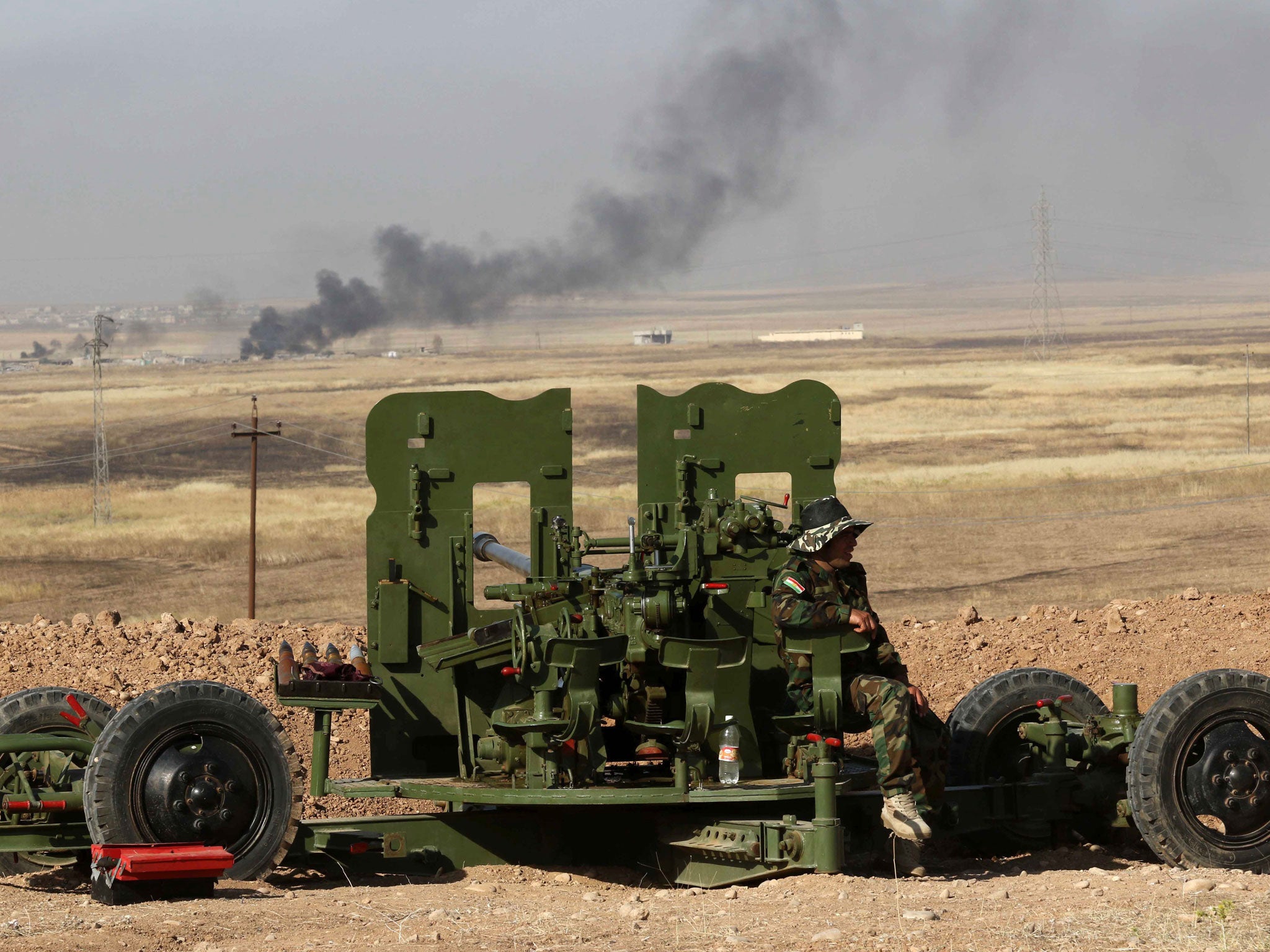 Smoke billows on the front line as an Iraqi Kurdish Peshmerga fighter holds a position near Hasan Sham village, some 45 kilometres east of the city of Mosul