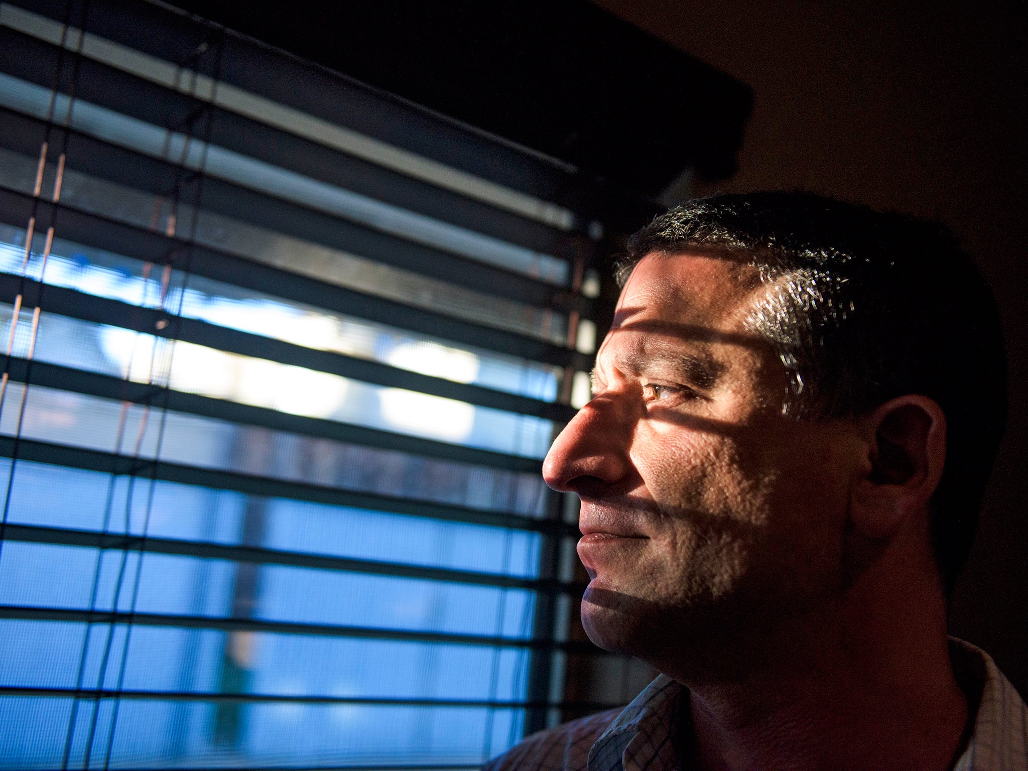 Keith Gartenlaub peers through blinds in the living room of his home in Southern California. Gartenlaub has been charged with possession of child pornography which he claims is a setup to confess to spy charges he has no knowledge of