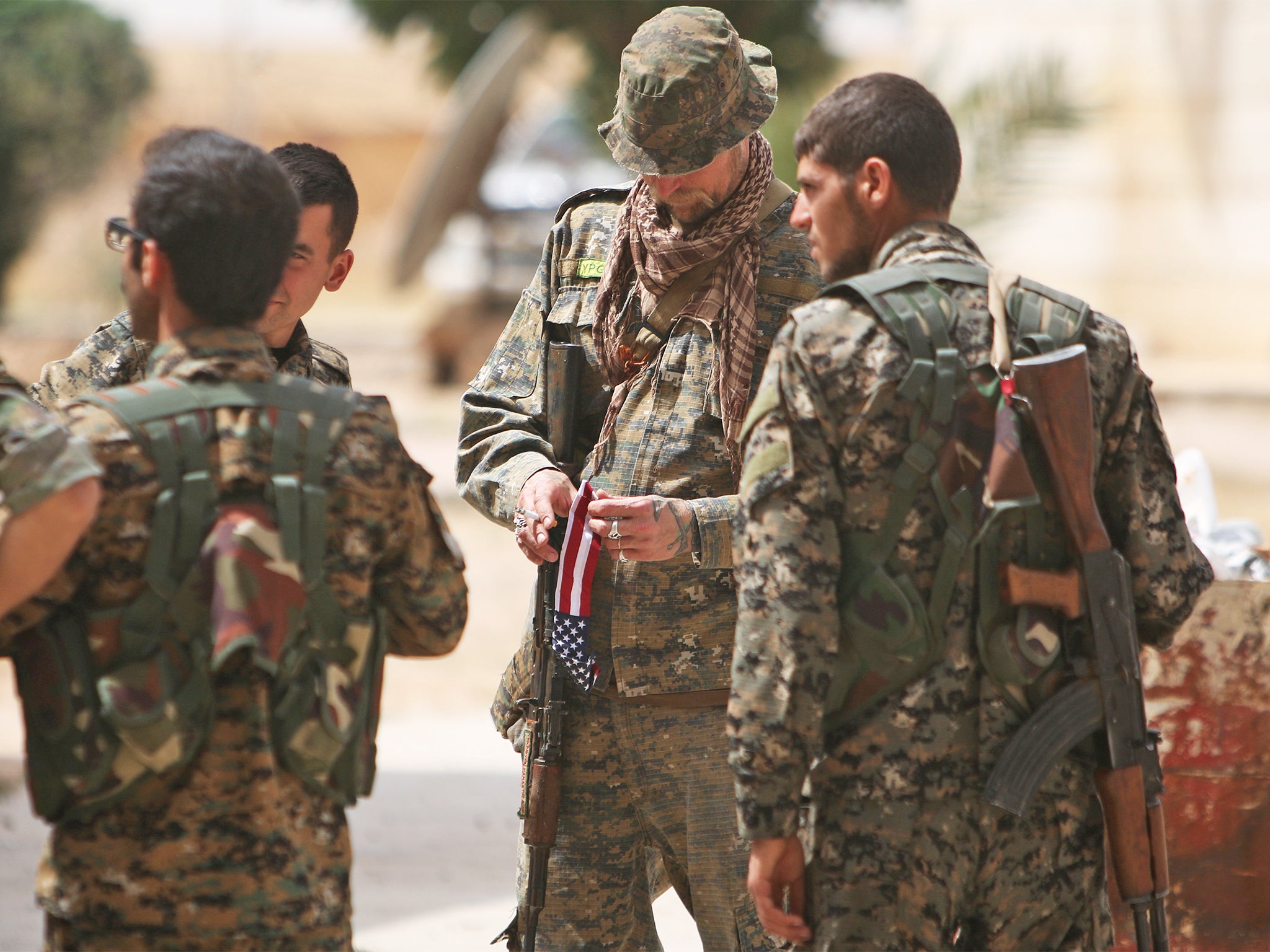 A US fighter, who is fighting alongside with Syria Democratic Forces (SDF), carries his national flag as he stands with SDF fighters in northern province of Raqqa,