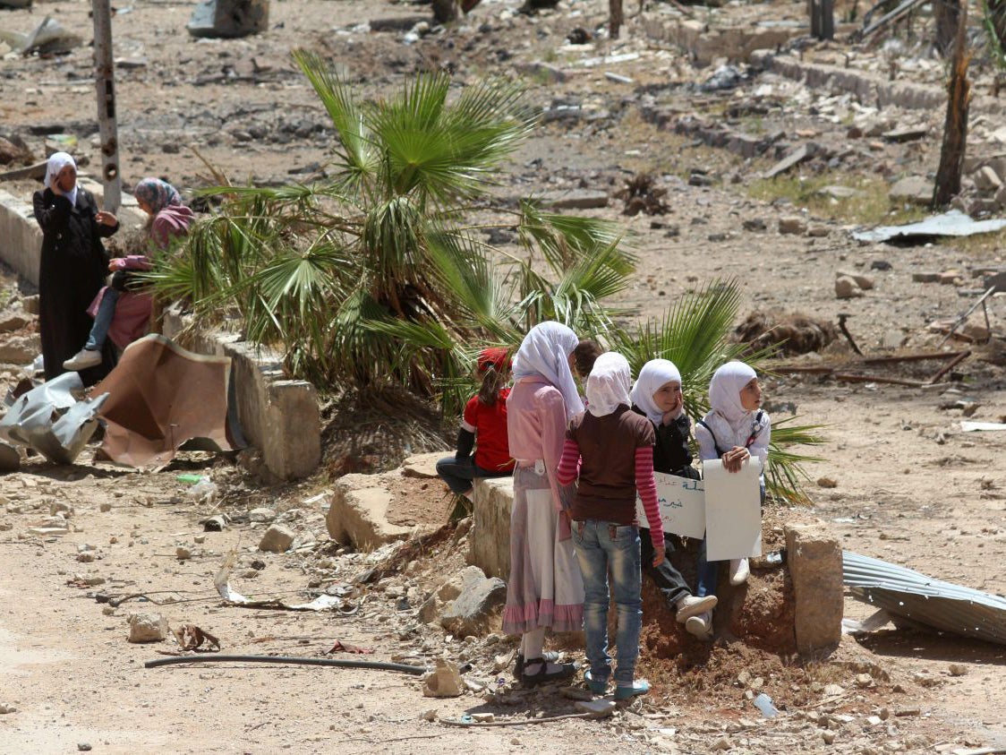 Syrian girls sit holding placards in the town of Daraya, southwest of central Damascus