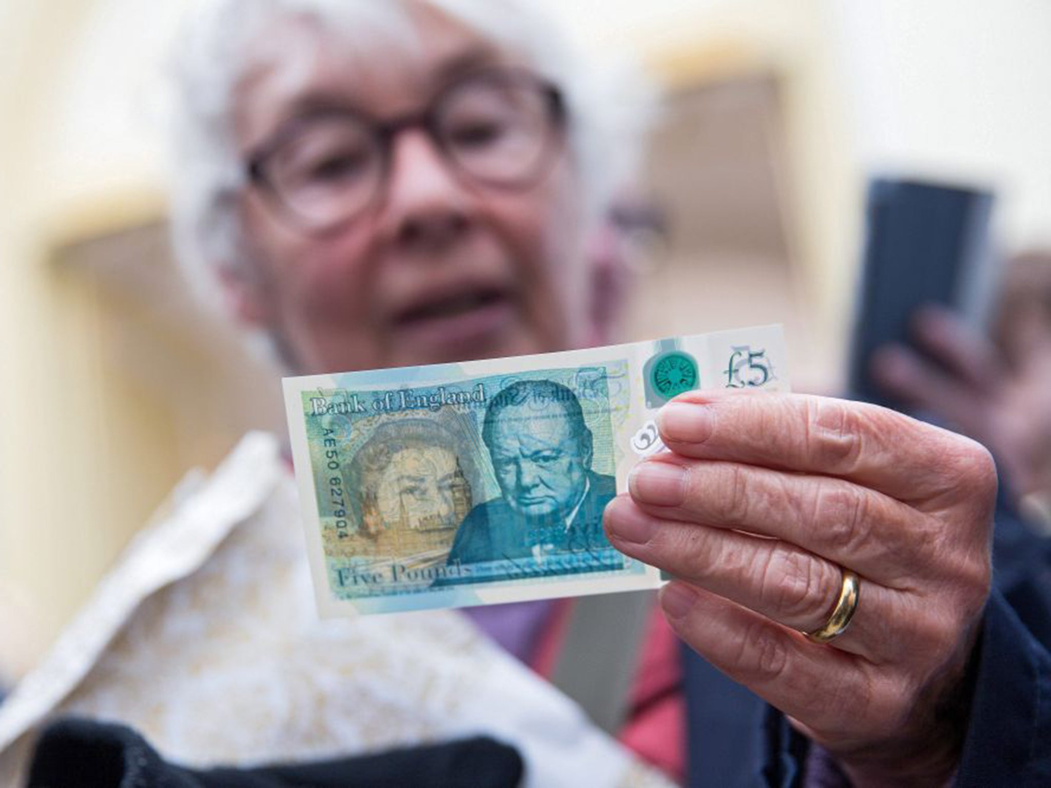 A woman surveys the new polymer £5 note