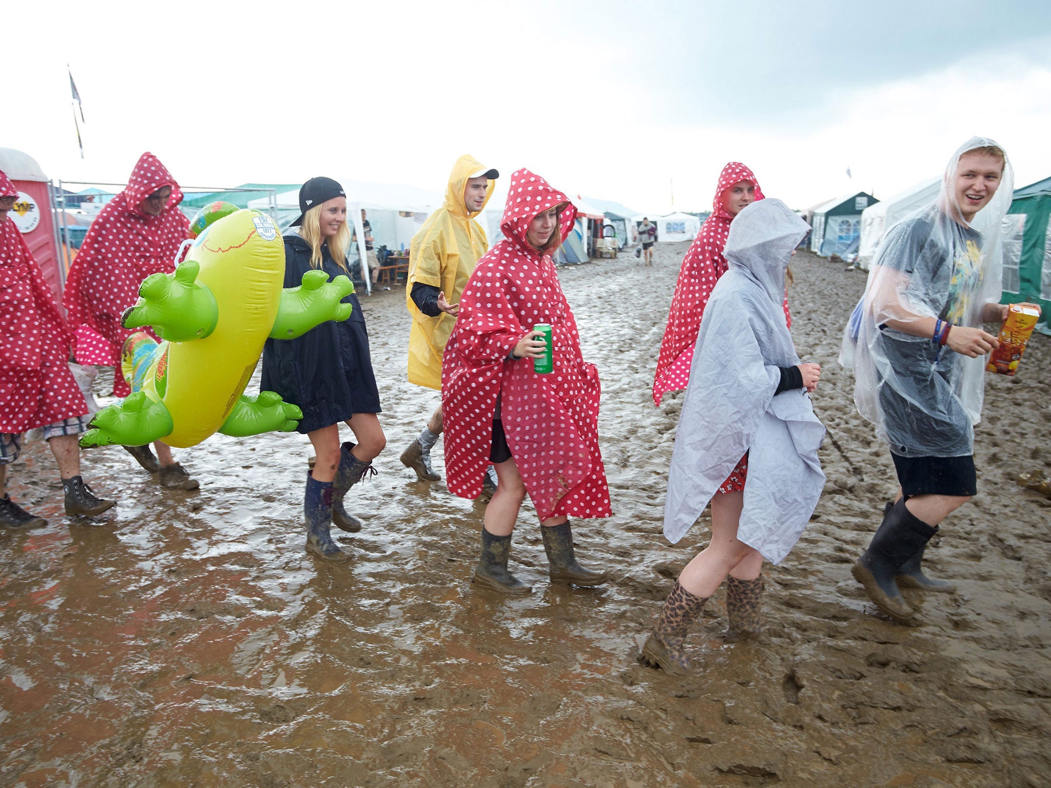 Rock fans from walk across the muddy camping area at the music festival 'Rock am Ring' in Mendig, Germany, 3 June 2016.