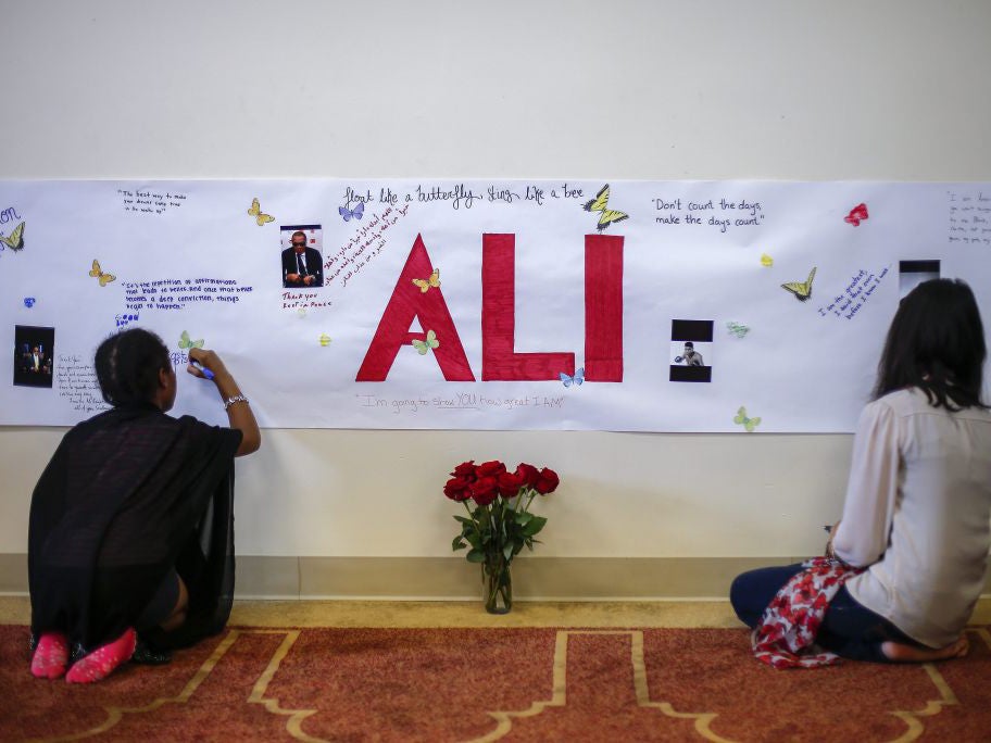 People write on a poster during the Interfaith Memorial Service at the Louisville Islamic Center for Muhammad Ali