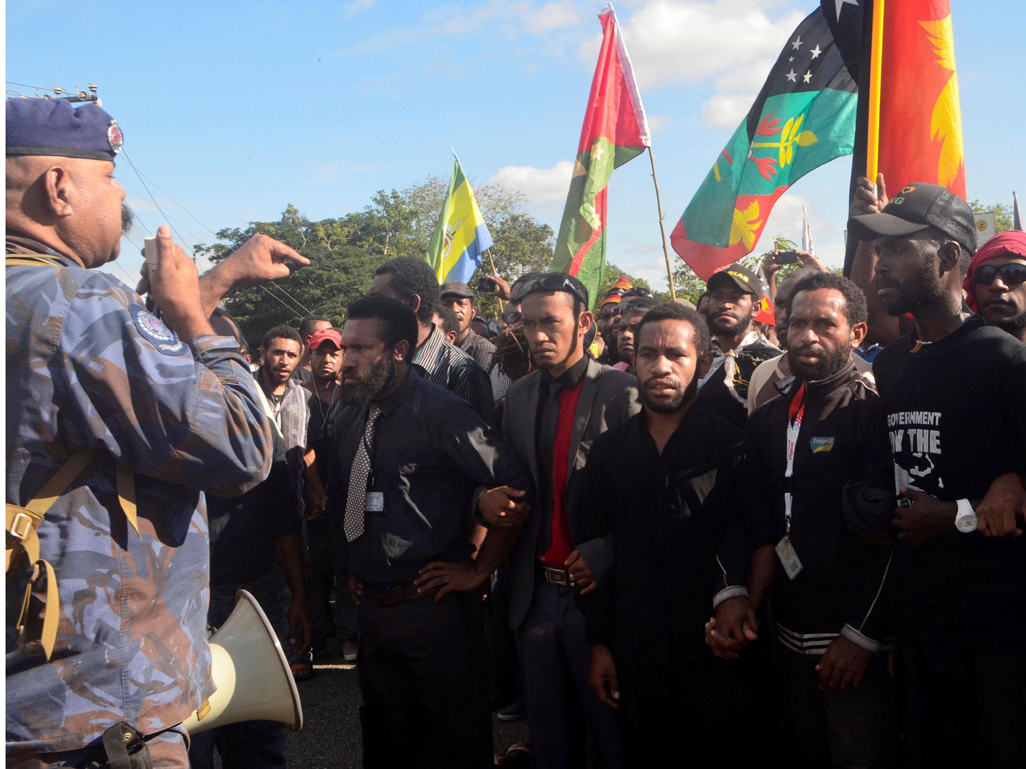 A Papua New Guinea police special services division officer talks through a megaphone as students attempt to march from University of Papua New Guinea in Port Moresby, Papua New Guinea