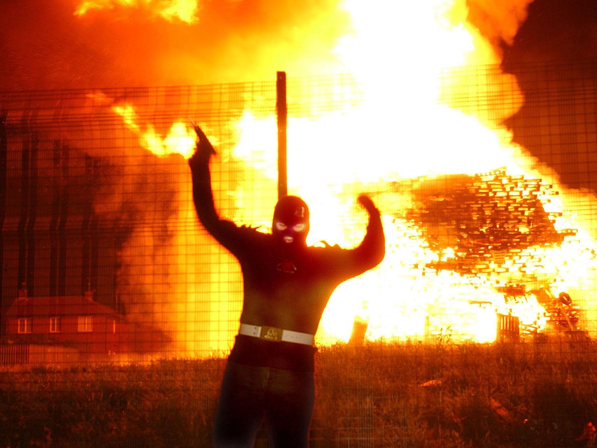 A masked Ulster Volunteer Force (UVF) gunman at a bonfire heralding the Twelfth of July parades across Northern Ireland