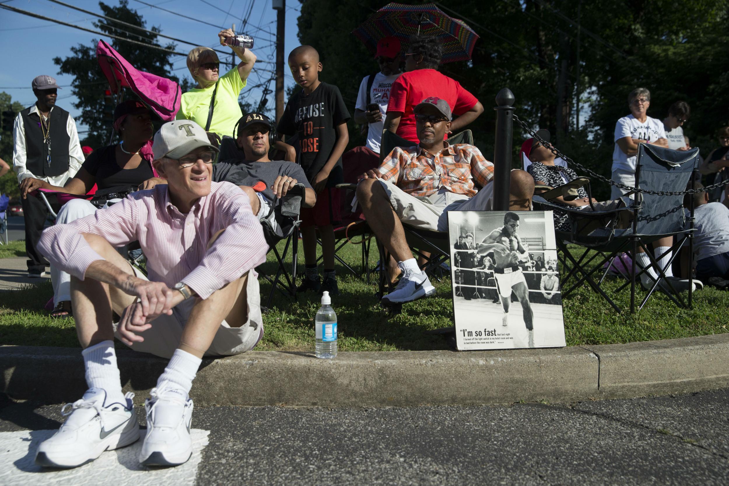 Fans line the street to watch the casket pass by