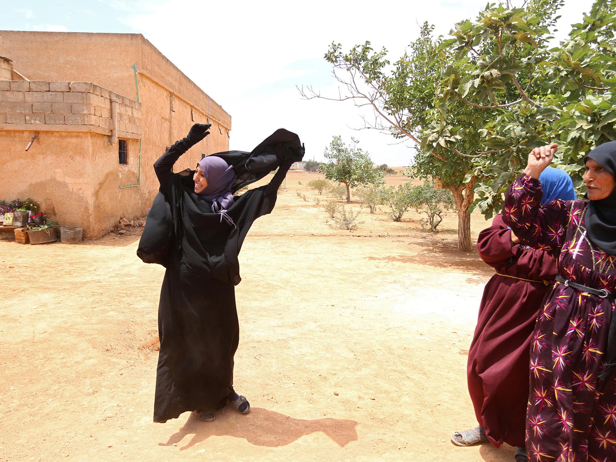 A woman removes her Niqab in a village on the outskirts of Manbij city after Syria Democratic Forces (SDF) fighters took control of it