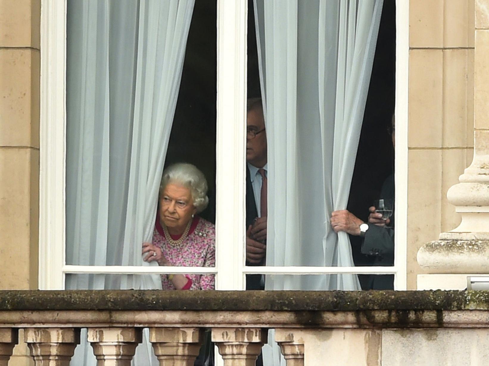 The Queen peers out of Buckingham Palace ahead of her appearance on the Mall