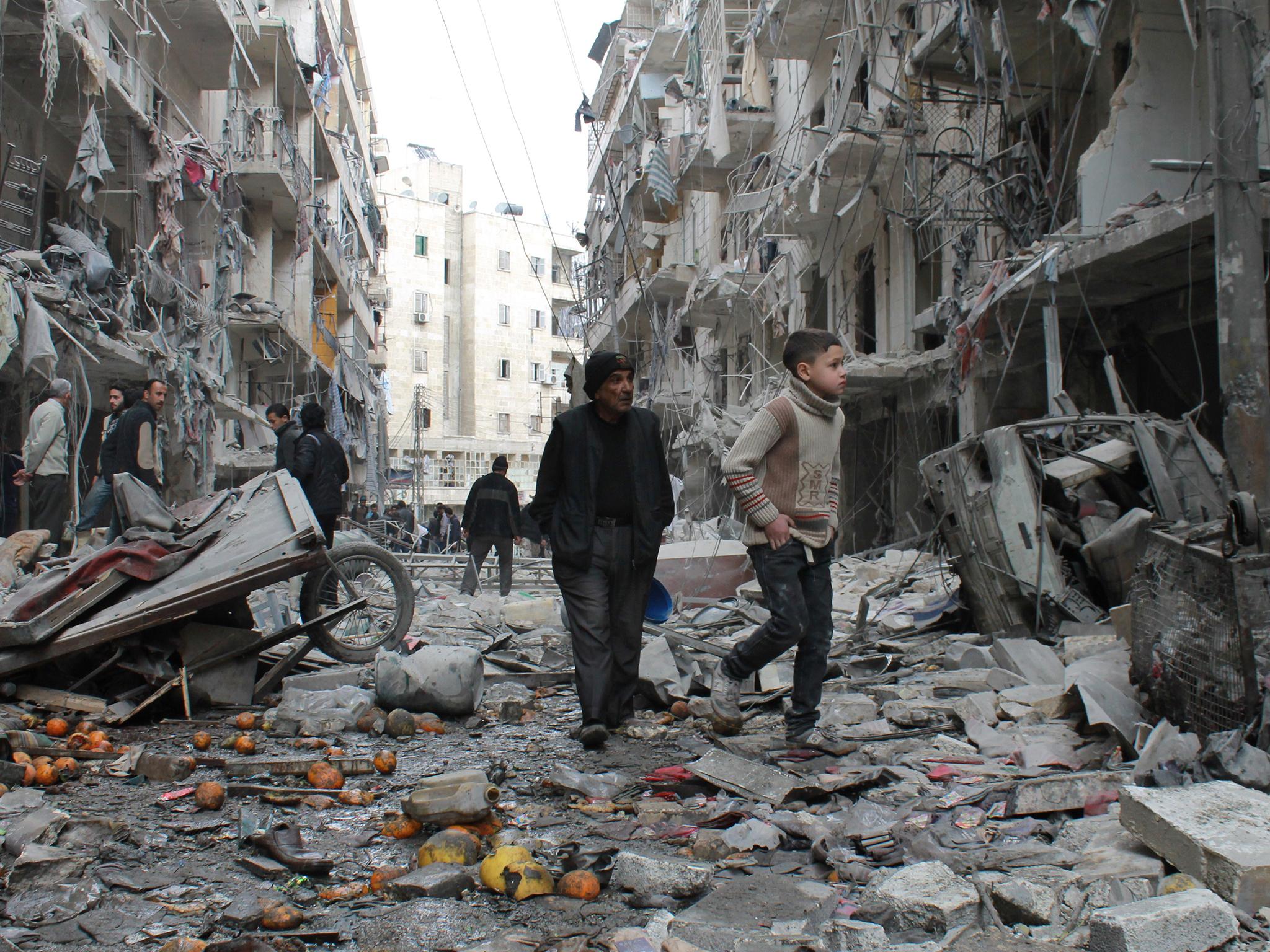 An elderly Syrian man and a child walk amidst debris in a residential block hit by explosives in Aleppo