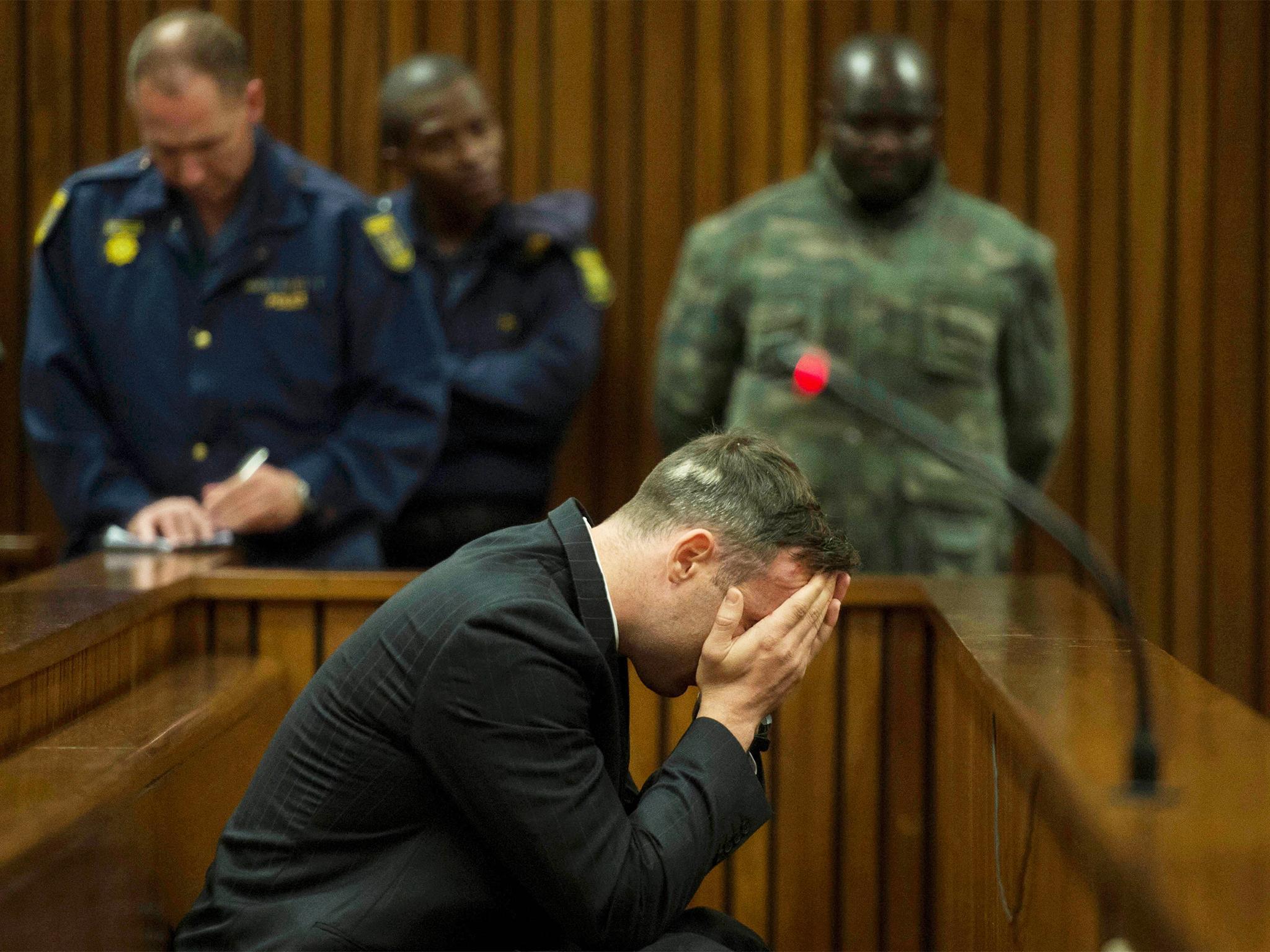 Oscar Pistorius covers his face as the father of his late girlfriend testifies at the Pretoria High Court yesterday