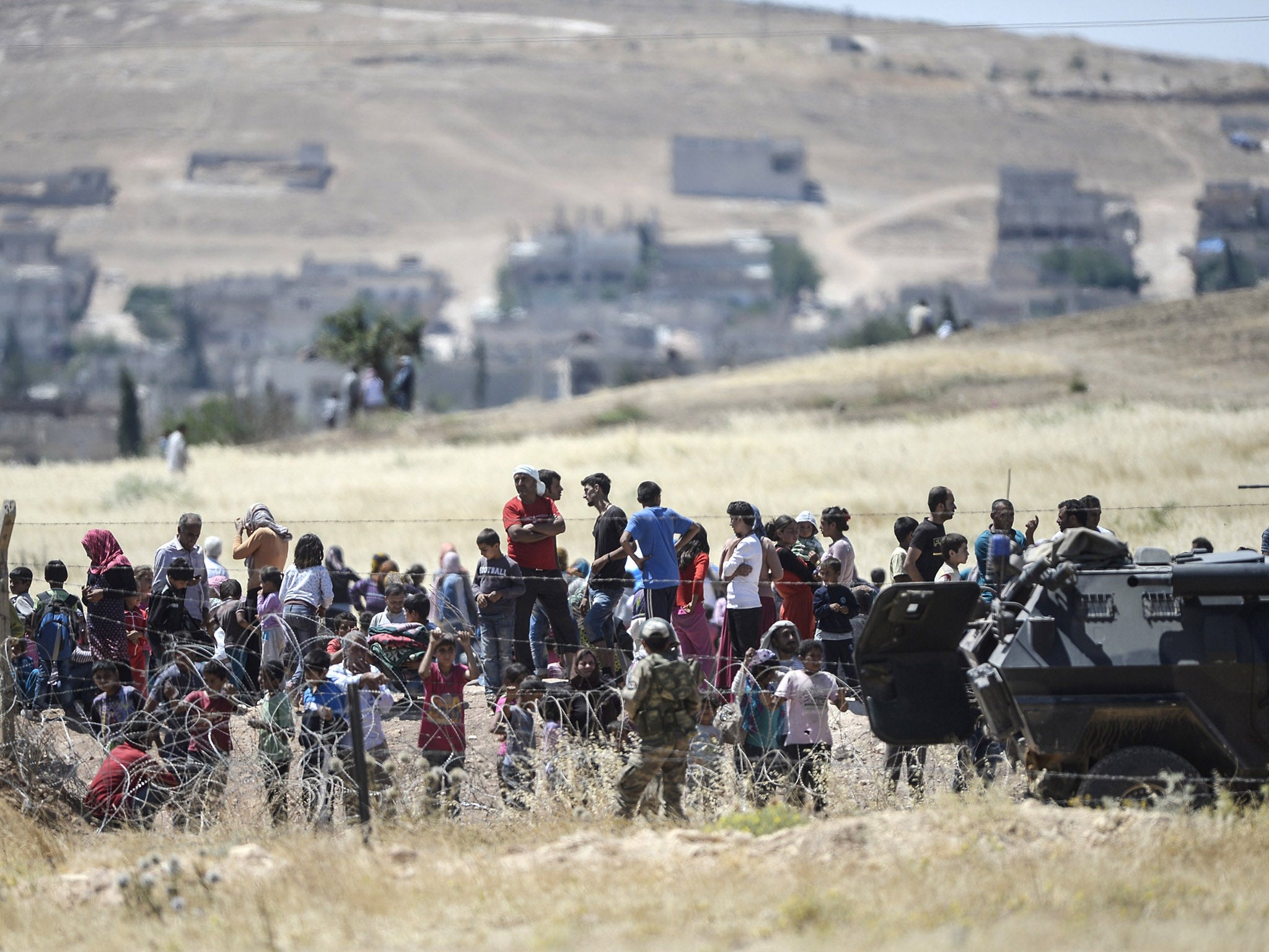 Turkish guards watch over Syrian refugees at the border