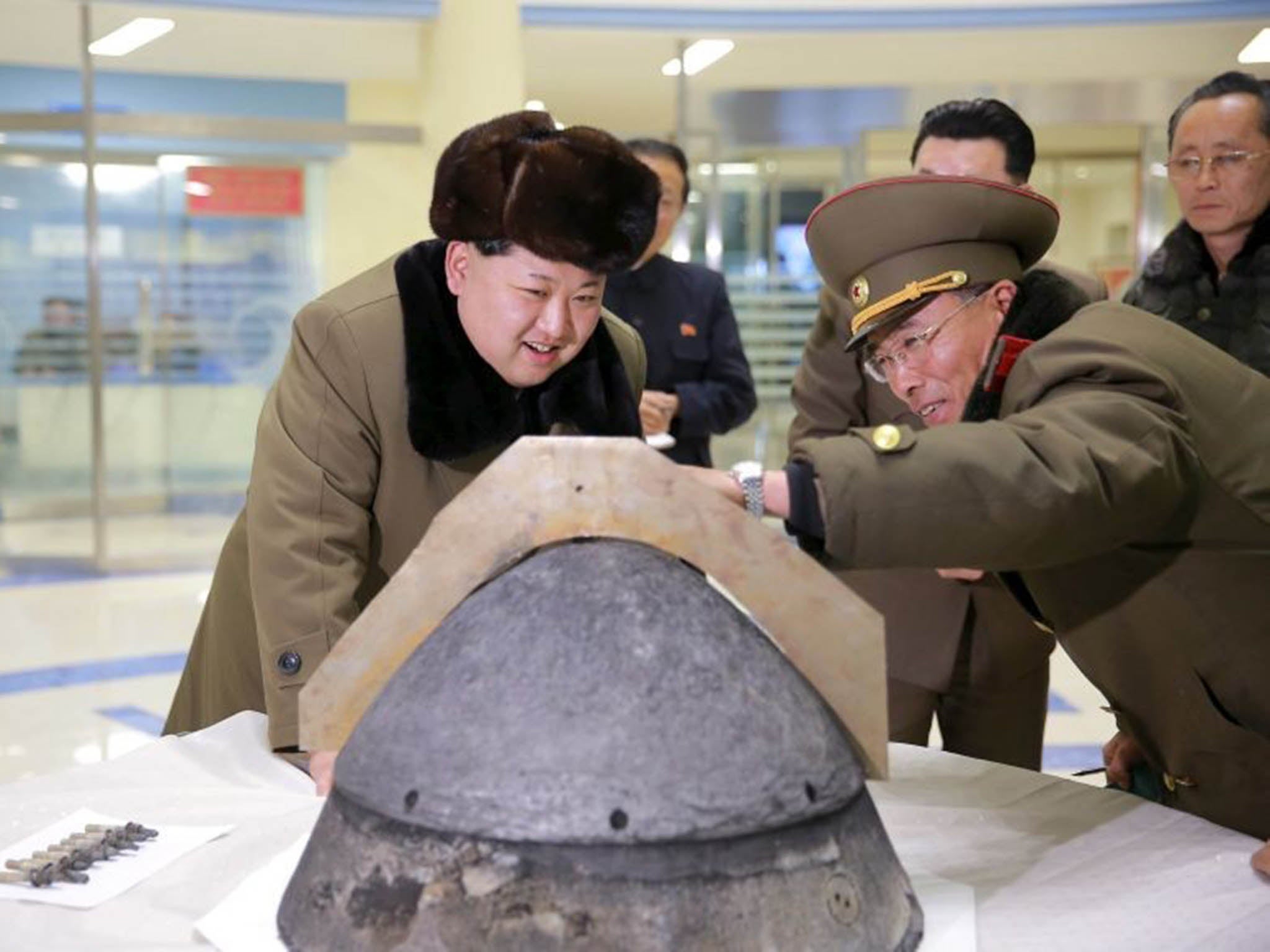 North Korean leader Kim Jong Un looks at a rocket warhead tip after a simulated test of atmospheric re-entry of a ballistic missile, at an unidentified location