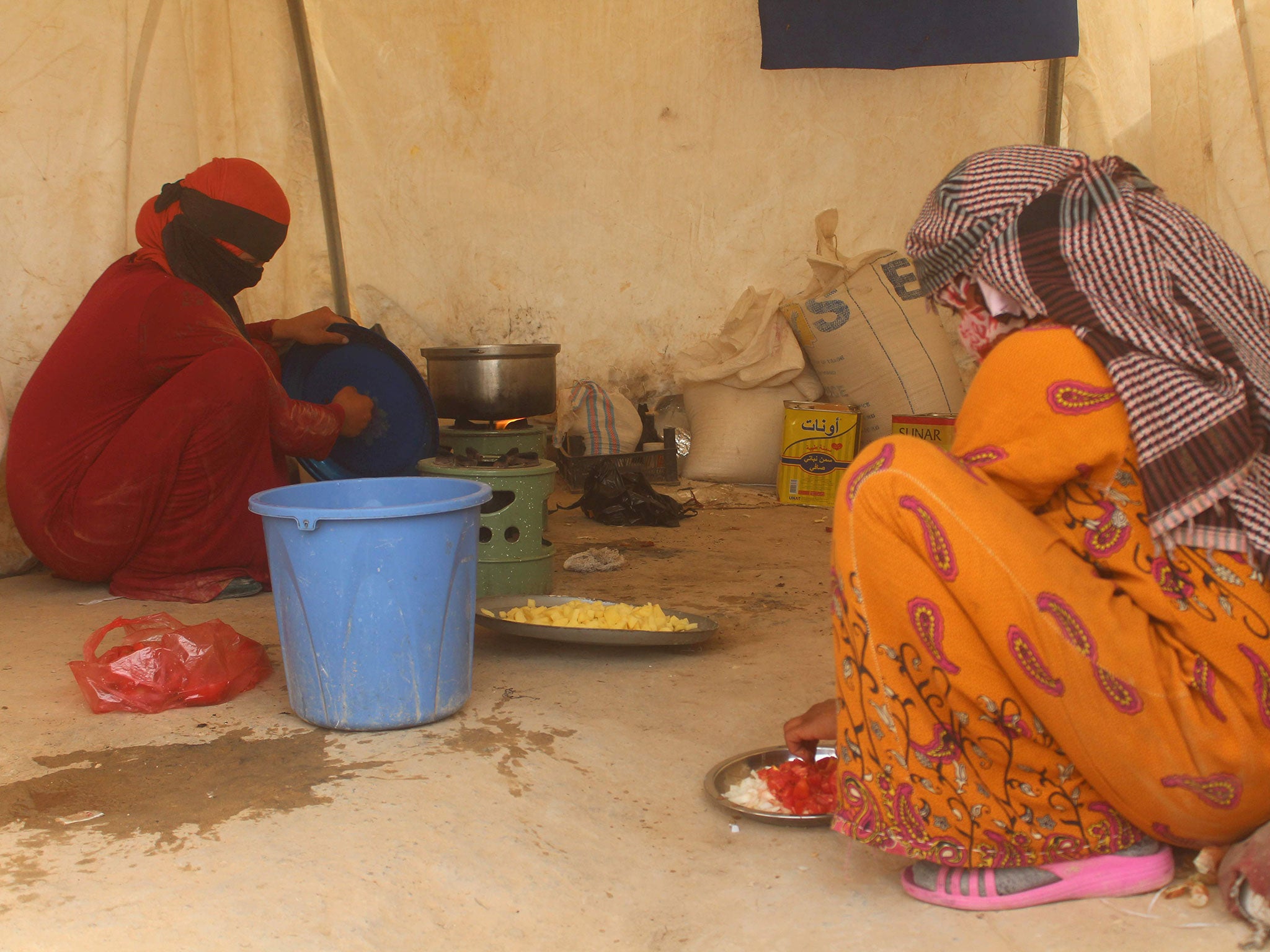 Displaced Iraqis from the embattled city of Fallujah cook at a camp on June 18, 2016.