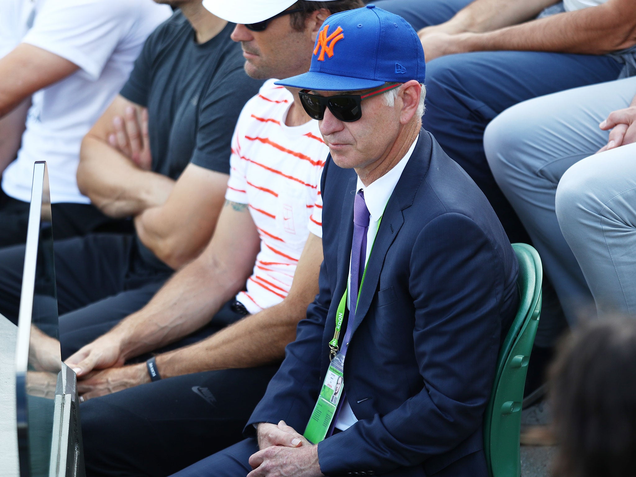 John McEnroe watches his new charge Milos Raonic in the first round