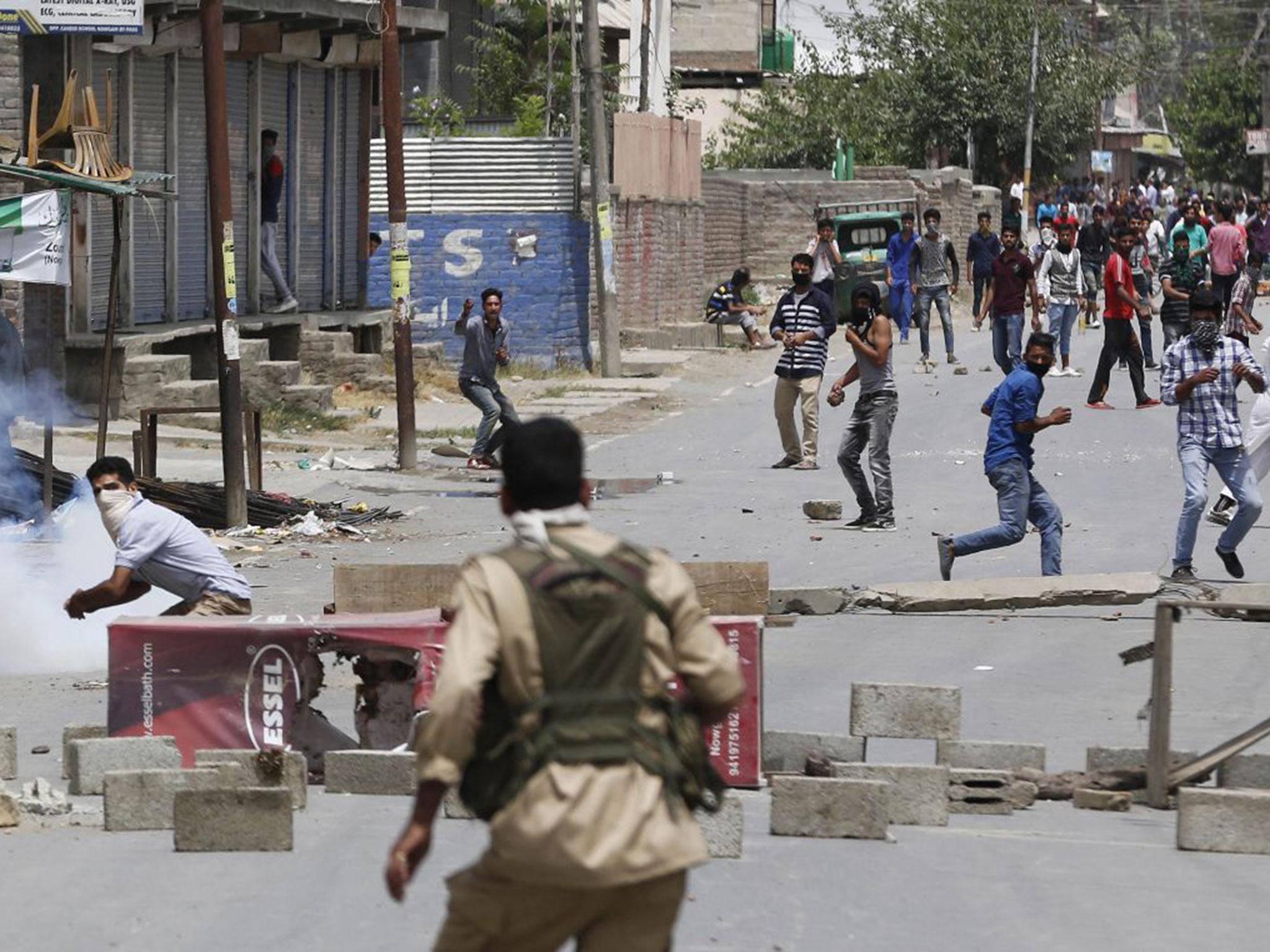 A masked Kashmiri protester prepares to throws a brick at an Indian policeman during a protest in Srinagar, Indian controlled Kashmir