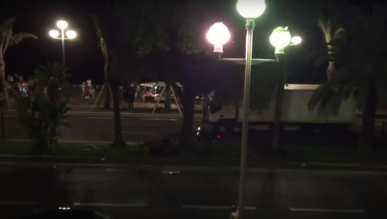 The lorry drives at high speed along the promenade. A motorbike travels beside it