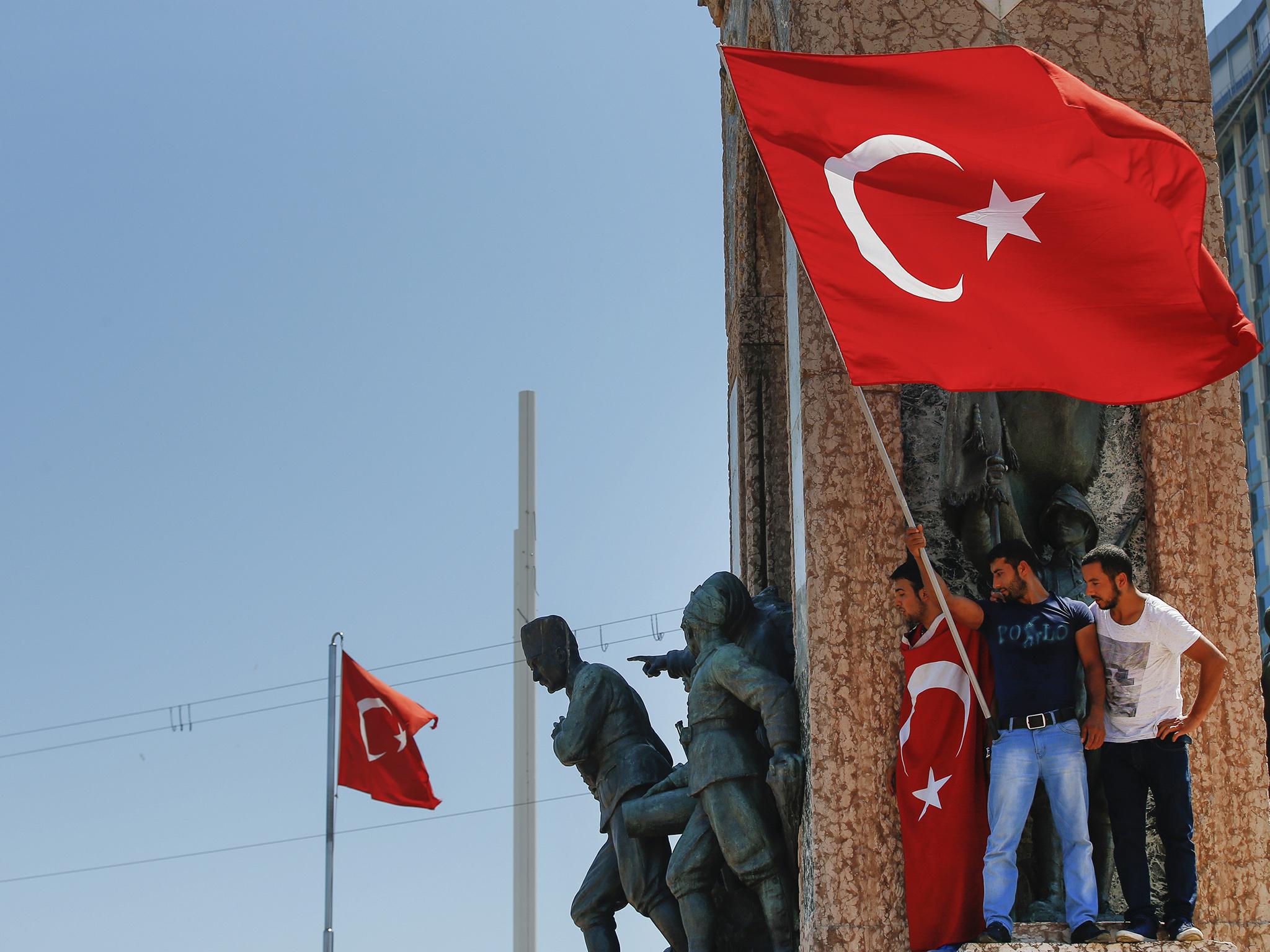 Anti-coup protesters wave a Turkish flag on top of the monument in Taksim square, Istanbul,