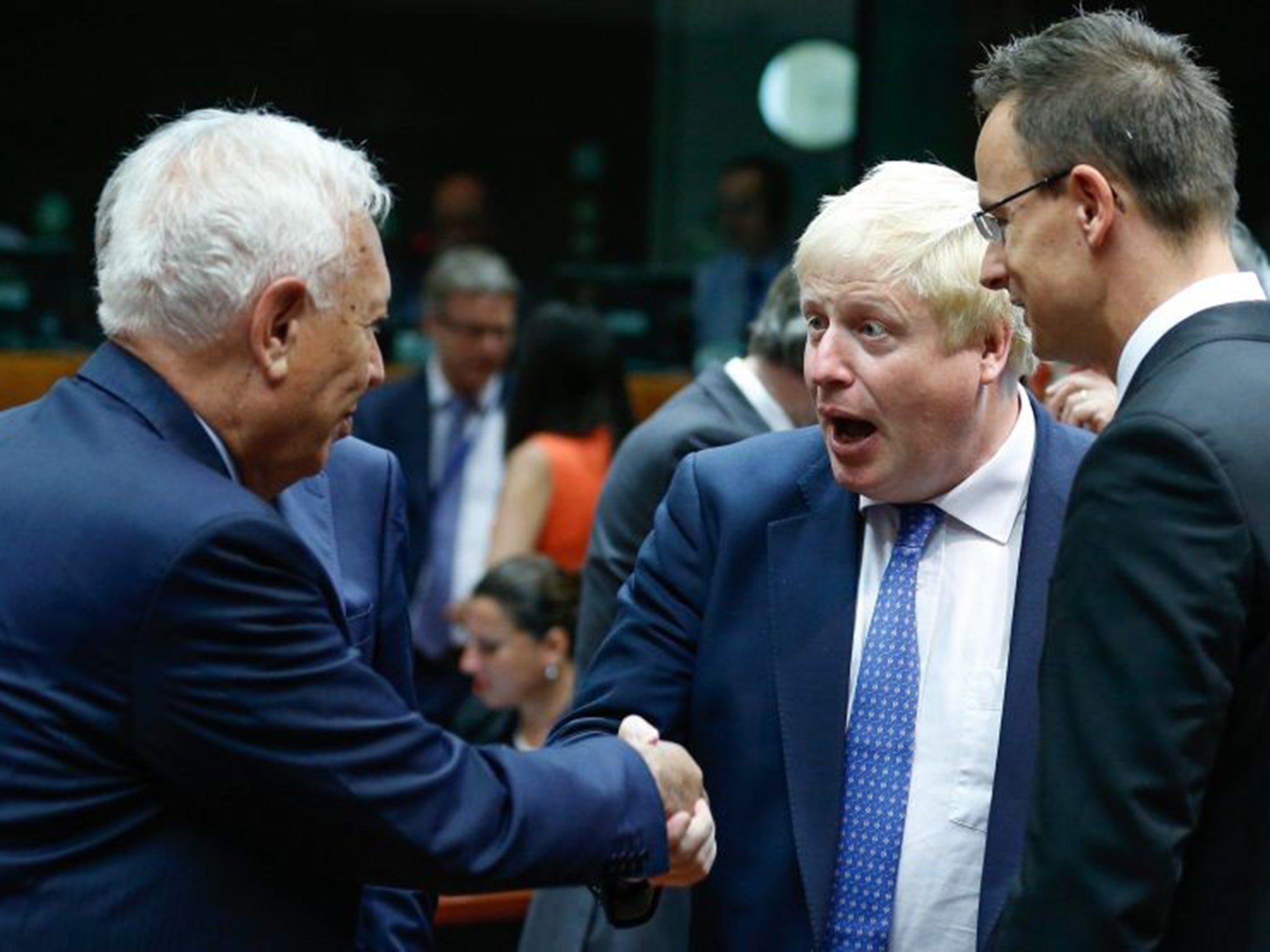 Britain's Foreign Secretary Boris Johnson (C) and Spanish Foreign Minister Jose Manuel Garcia-Margallo (L) shake hands during an EU Foreign Affairs Council meeting