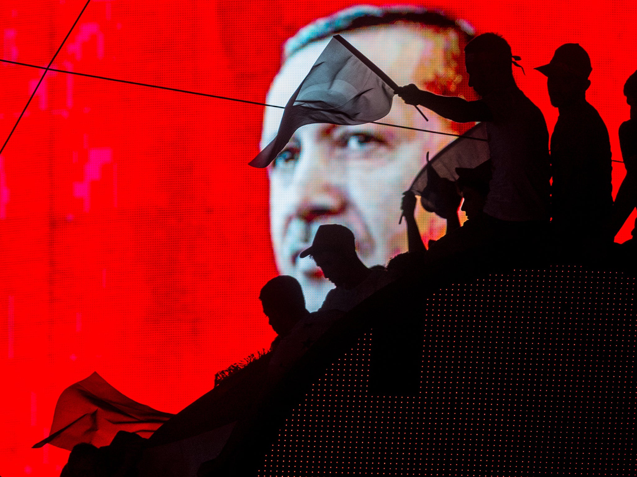 Government supporters wave Turkish flags in front of an electronic billboard displaying the face of President Erdogan in Ankara