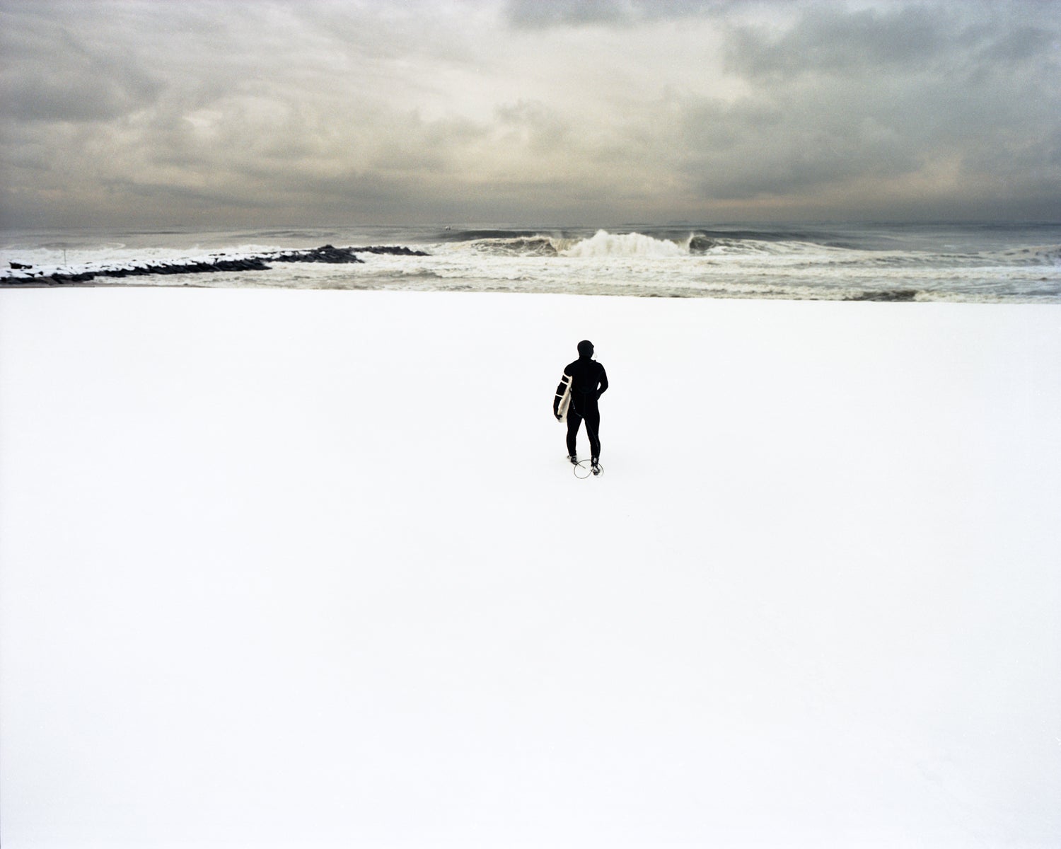 Kui, February Swell, 2005. A New York surfer rushes across a snowed covered beach to surf a cresting wave