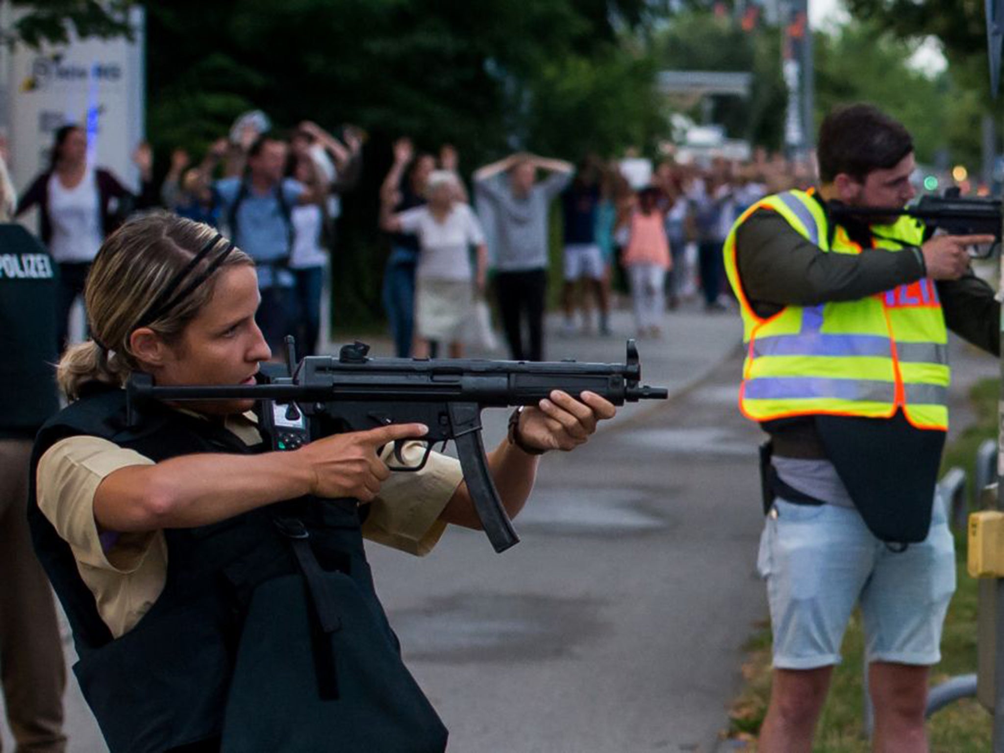 Police officers guard with guns as they escort people near from inside the shopping centre as they respond to a shooting at the Olympia Einkaufzentrum (OEZ) at July 22, 2016 in Munich, Germany.