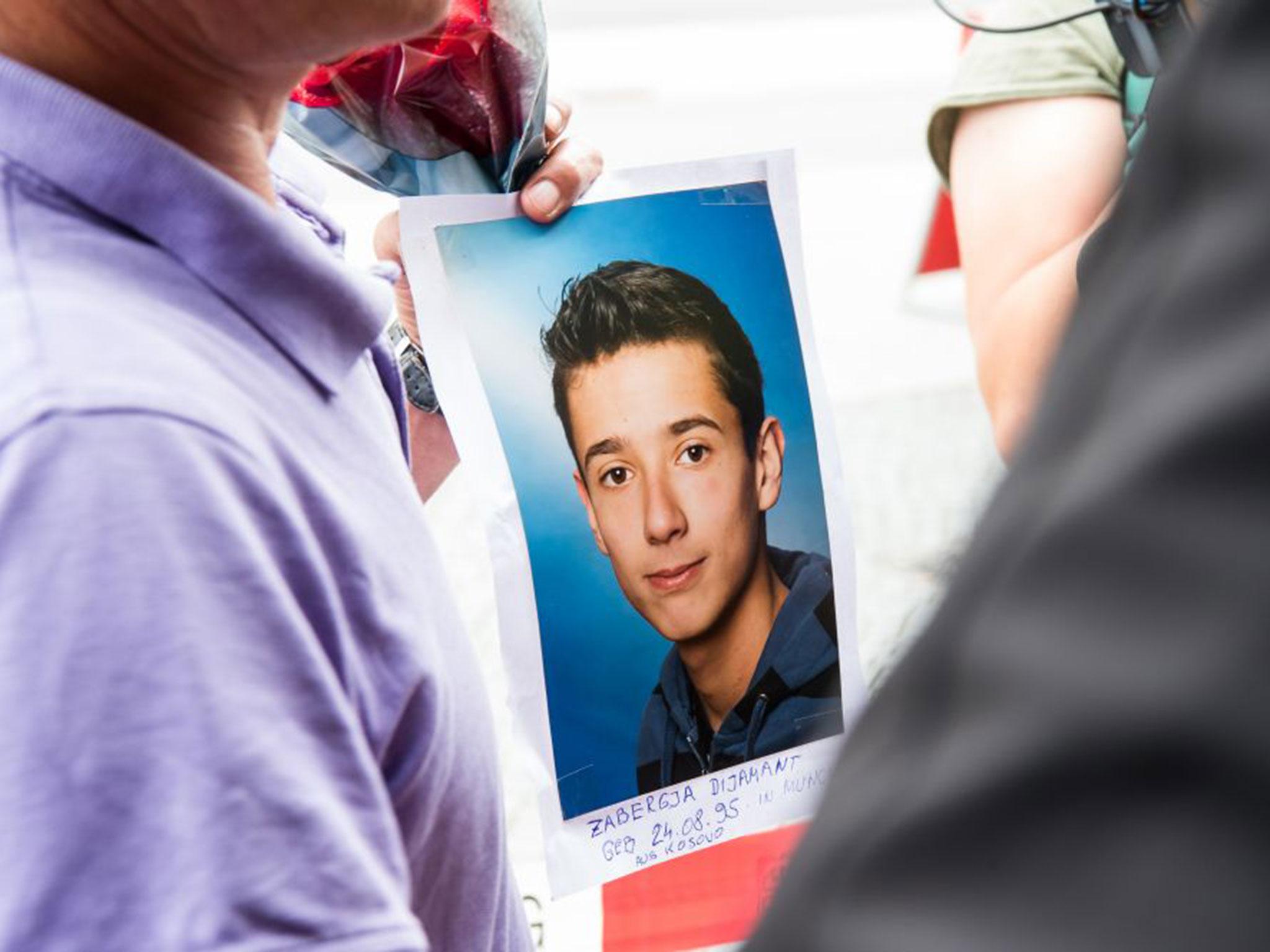 The father of one of the victims carries flowers and a picture of his son, Dijamant Zabergja (Joerg Koch/Getty)