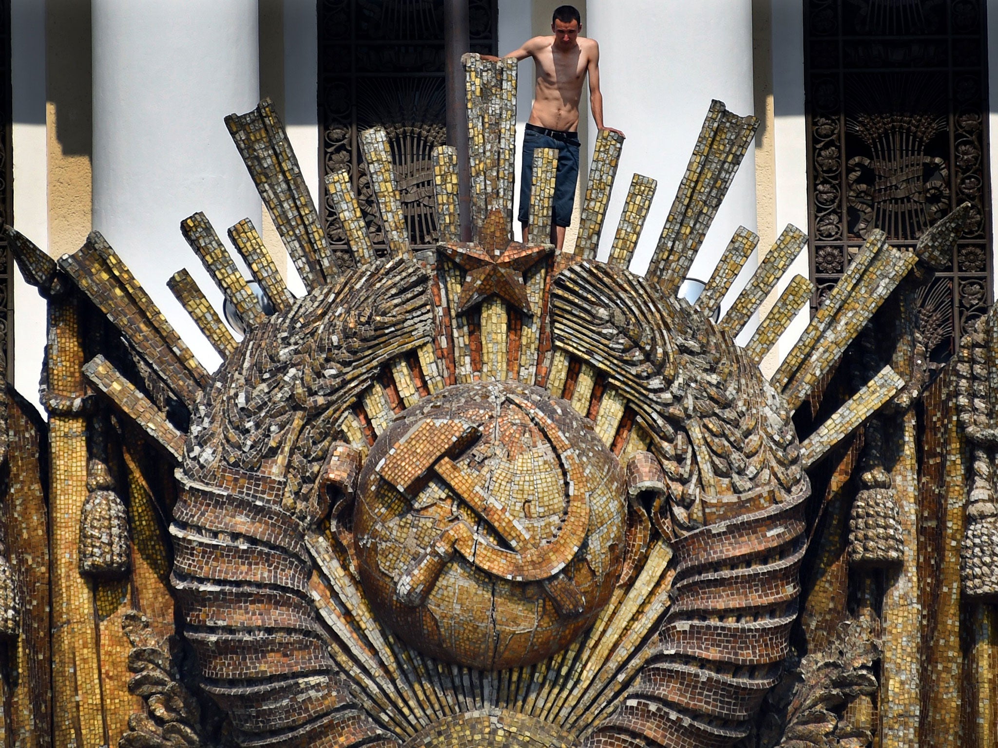 A worker climbs up to the Soviet Union state emblem during the restoration work atop the Central Pavilion at the VDNKh