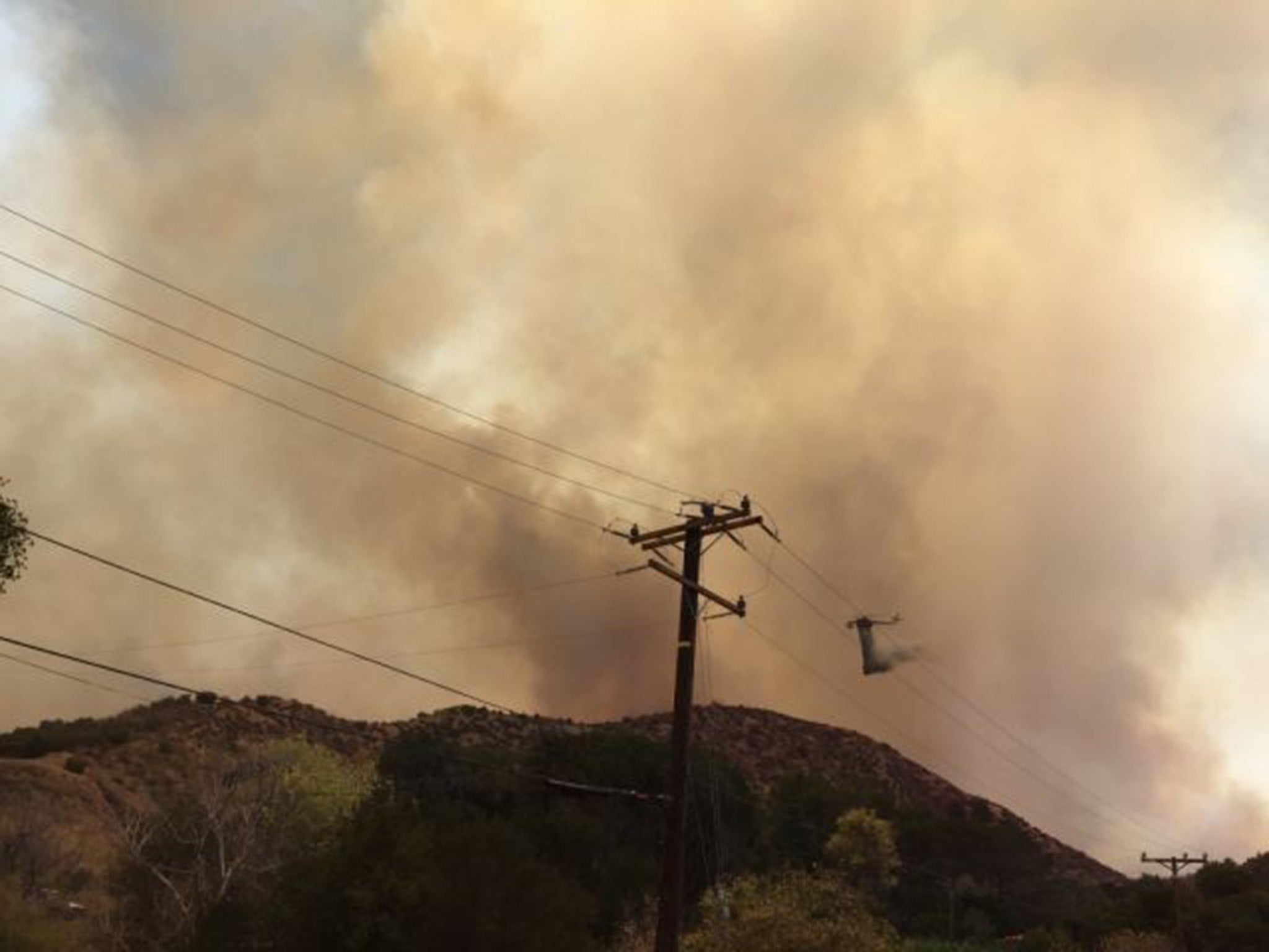 A helicopter drops water on a wildfire burning in Santa Clarita, California