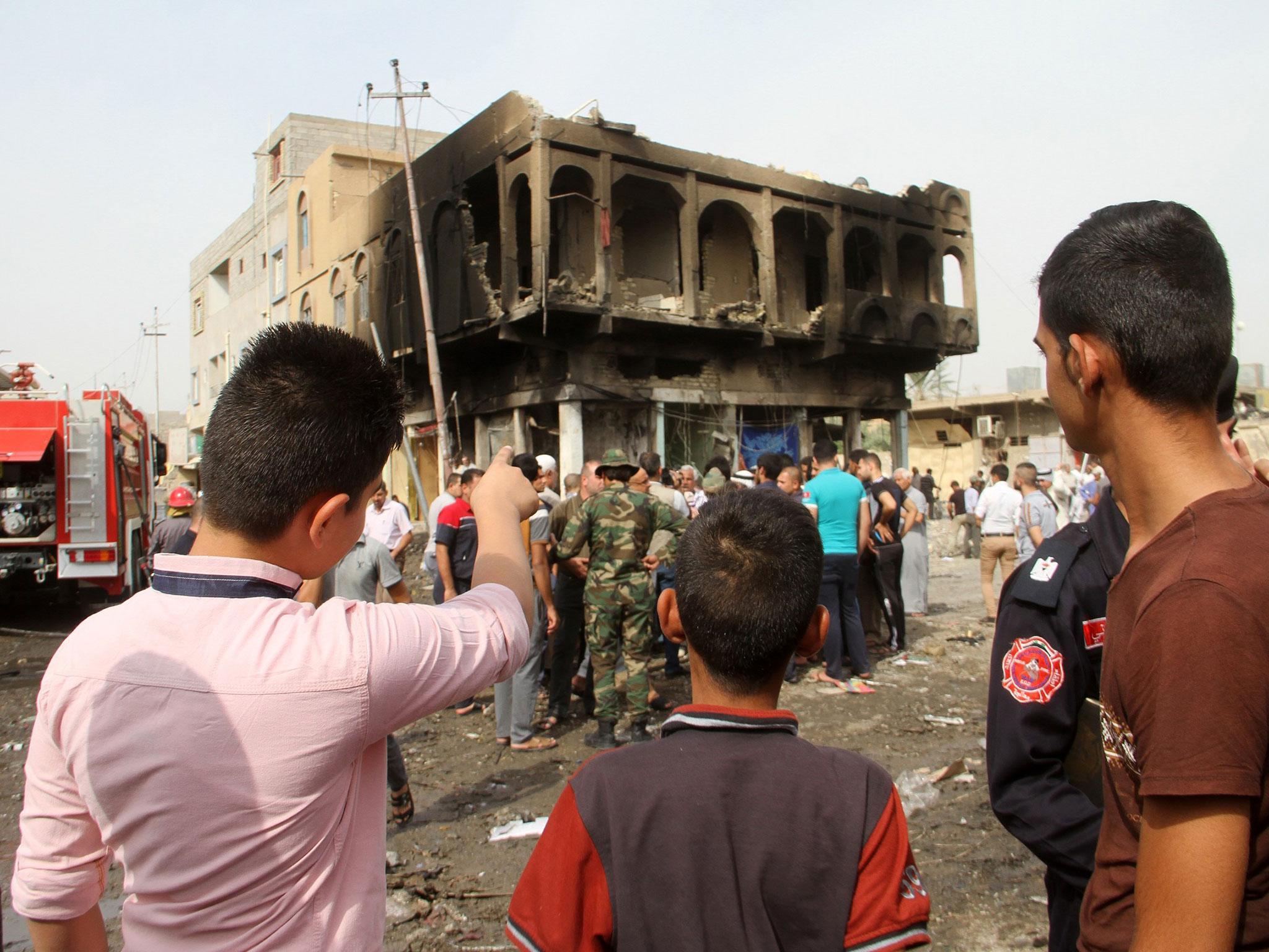 Iraqis look at a damaged building on October 6, 2015, a day after a blast in a market area of Khalis, around 55 kilometres from the capital Baghdad