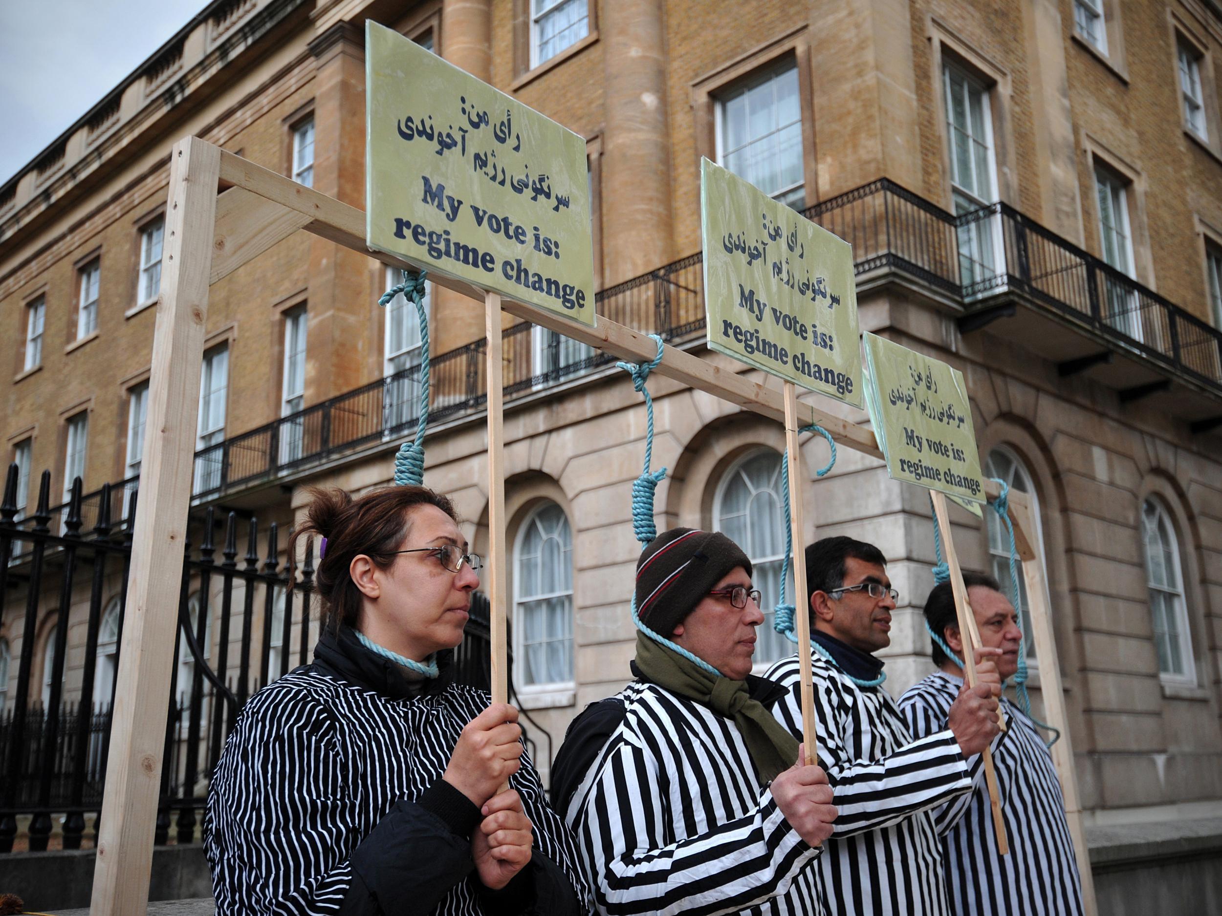 Iranian opposition protesters stand through makeshift nooses as they stage a mock execution during a rally against the Iranian regime in central London.