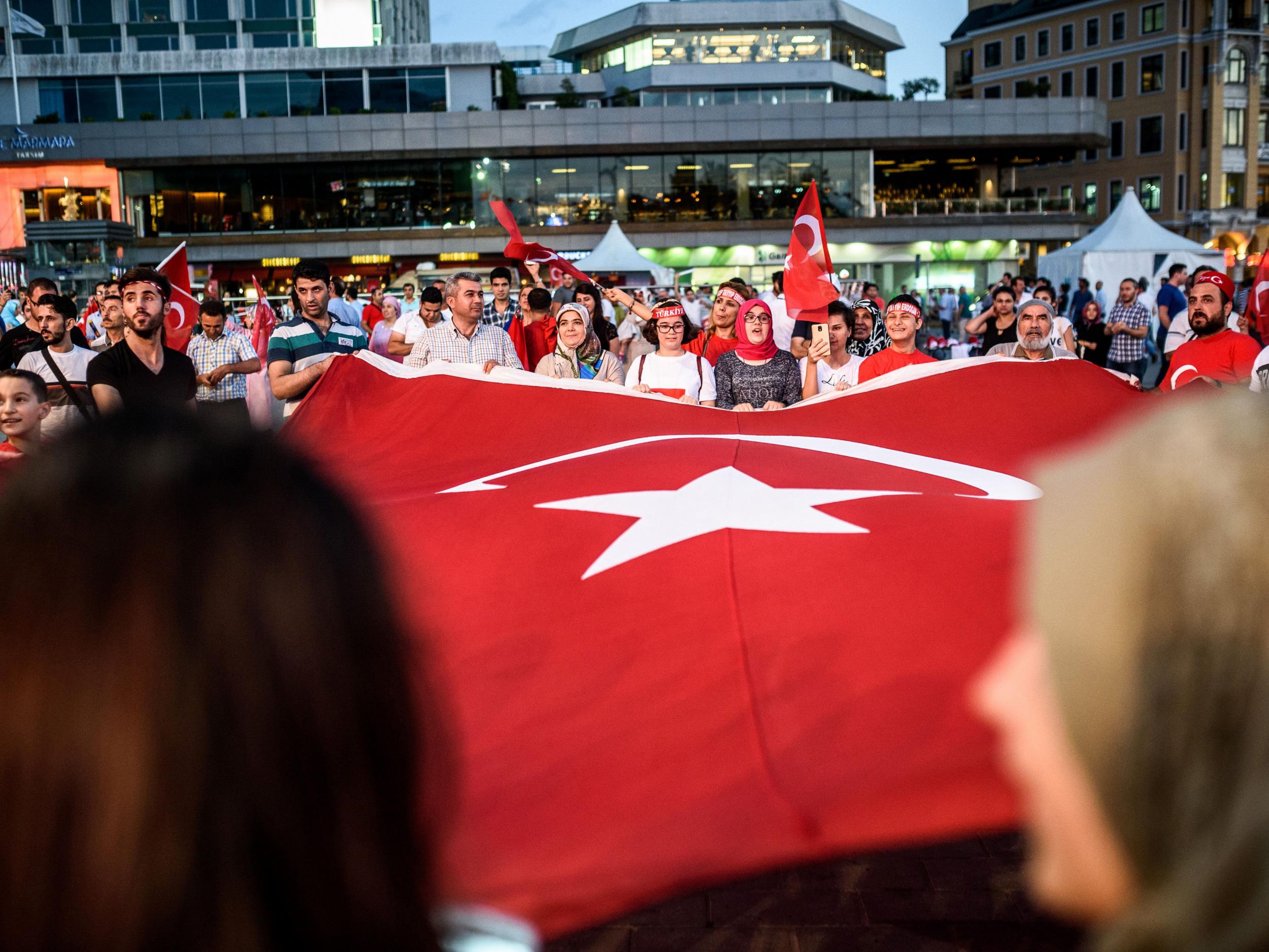 Pro-Erdogan supporters wave a giant Turkish national flag during a rally against the military coup on Taksim square in Istanbul