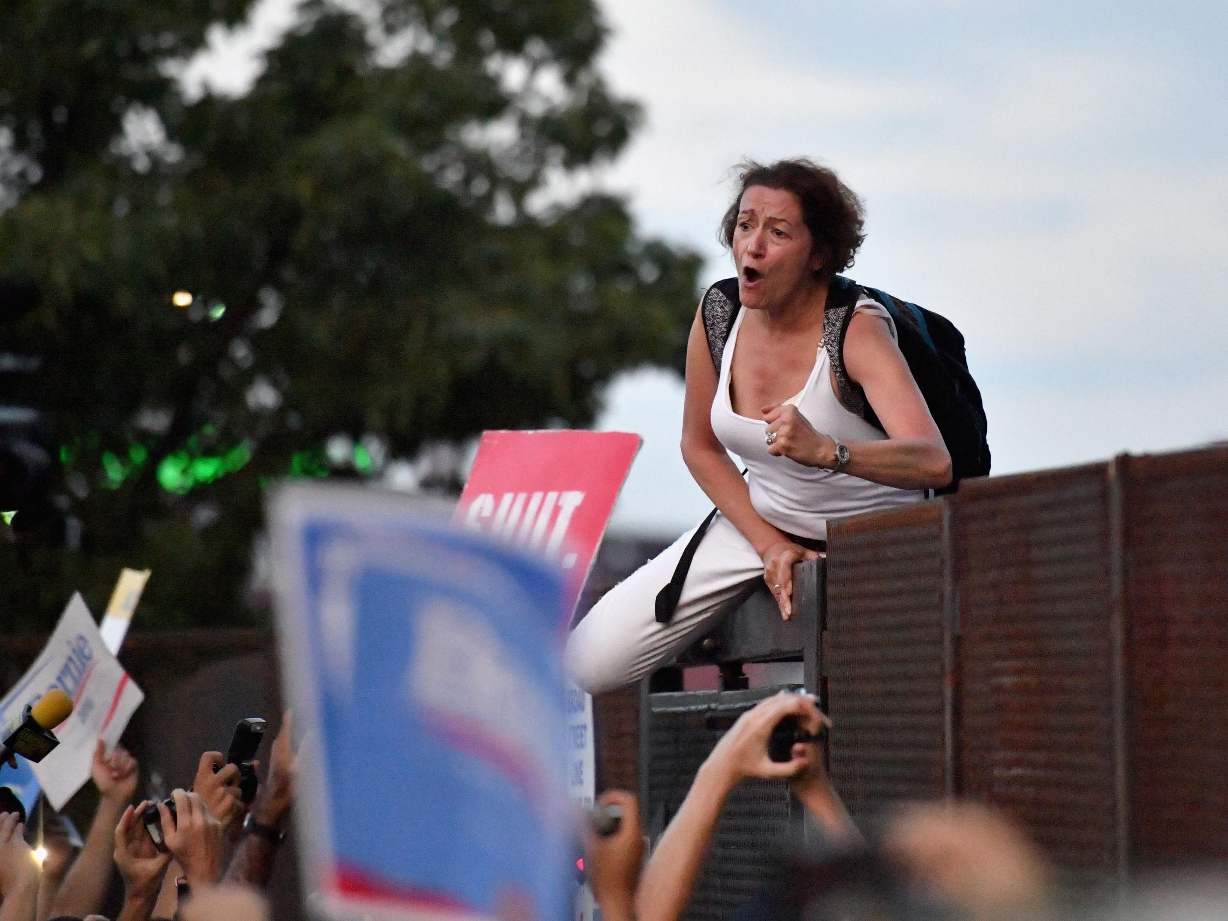 Protesters climb a fence near Wells Fargo Center on the second day of the Democratic National Convention.