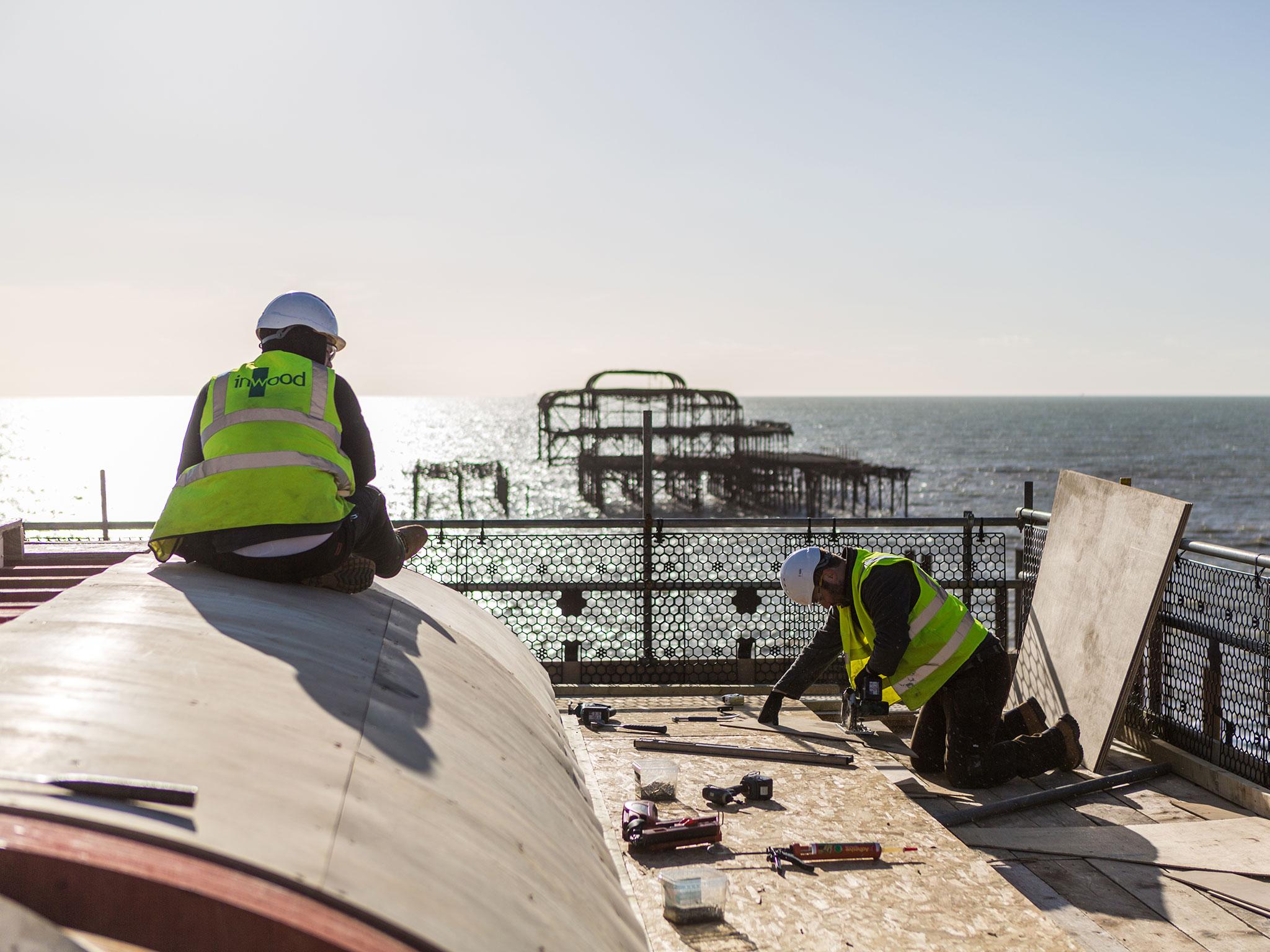 Carpenters work on the reconstructed east toll booth at the Brighton i360.