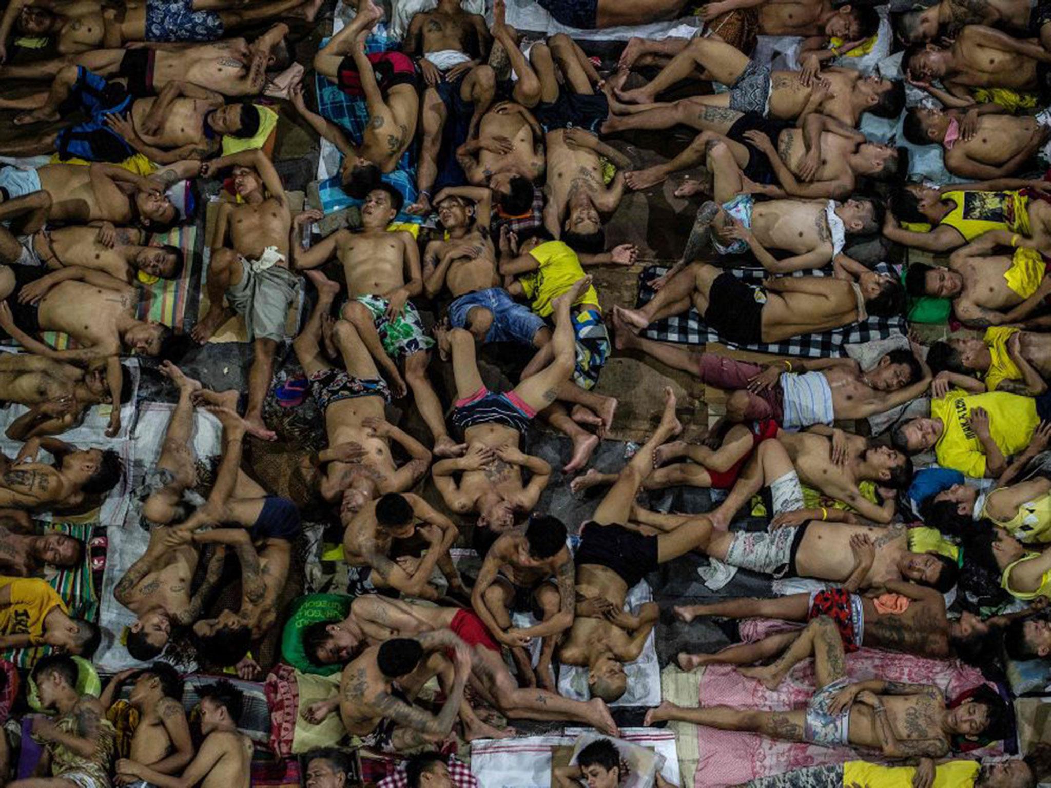 Inmates sleep on the ground of an open basketball court inside the Quezon City jail (AFP/Noel Celis)