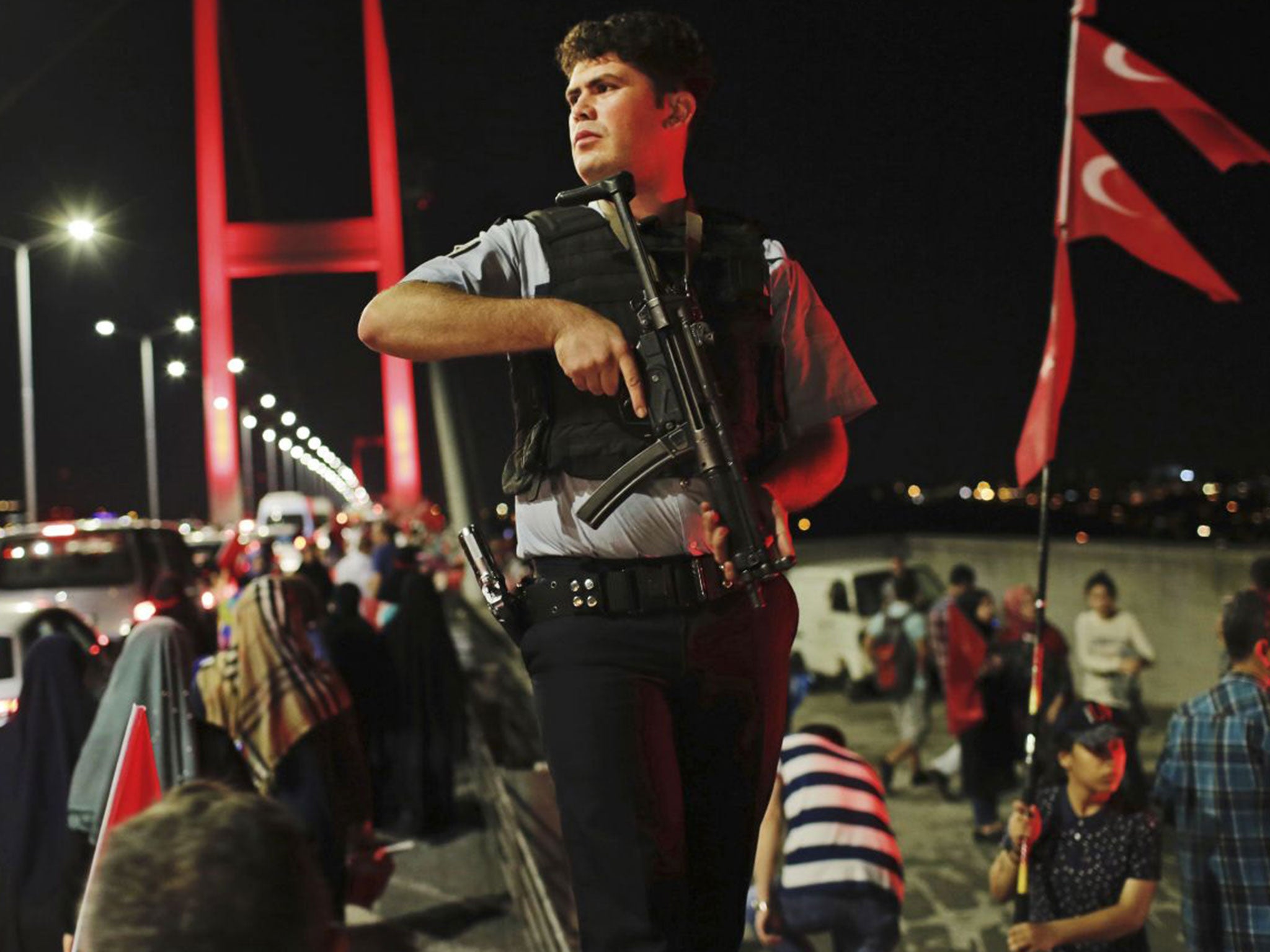 A Turkish police officer patrols as pro-government supporters, gather on Istanbul's iconic Bosporus Bridge, Thursday, July 21, 2016.