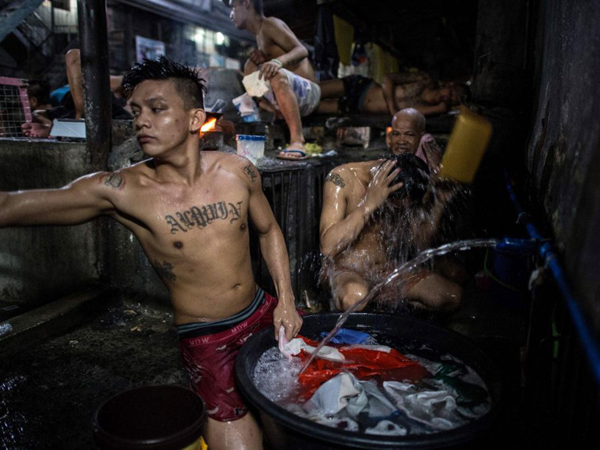 An inmate (middle centre) cooks his dinner as other detainees take a bath inside the Quezon City jail (AFP/Noel Celis)