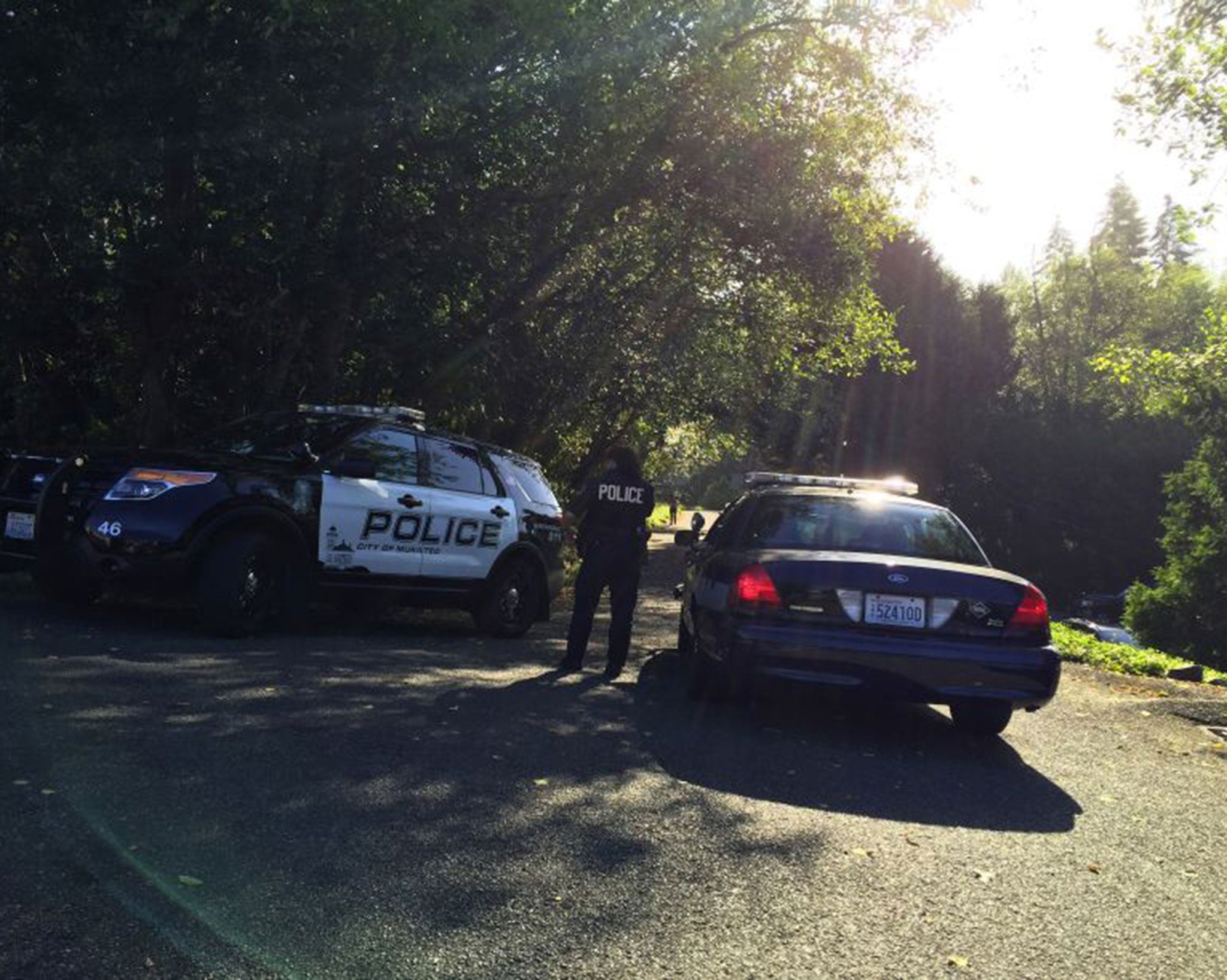 Police block the road leading to the house where three people were shot dead early Saturday