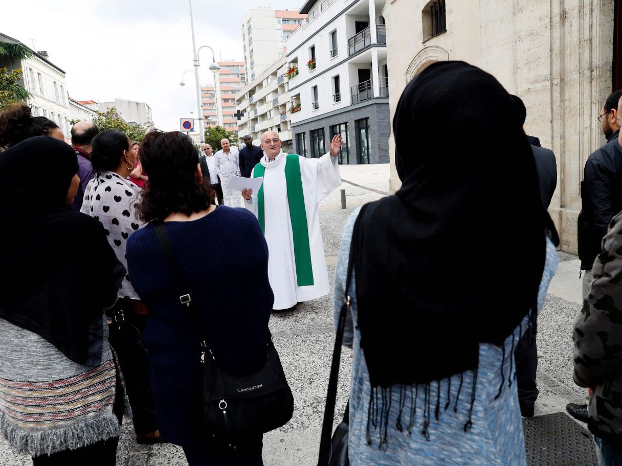 Bagnolet's priest Patrick Morvan (C) invites Christian and Muslim worshippers to enter the Saint-Leu Church to attend a mass in tribute to Father Jacques Hamel