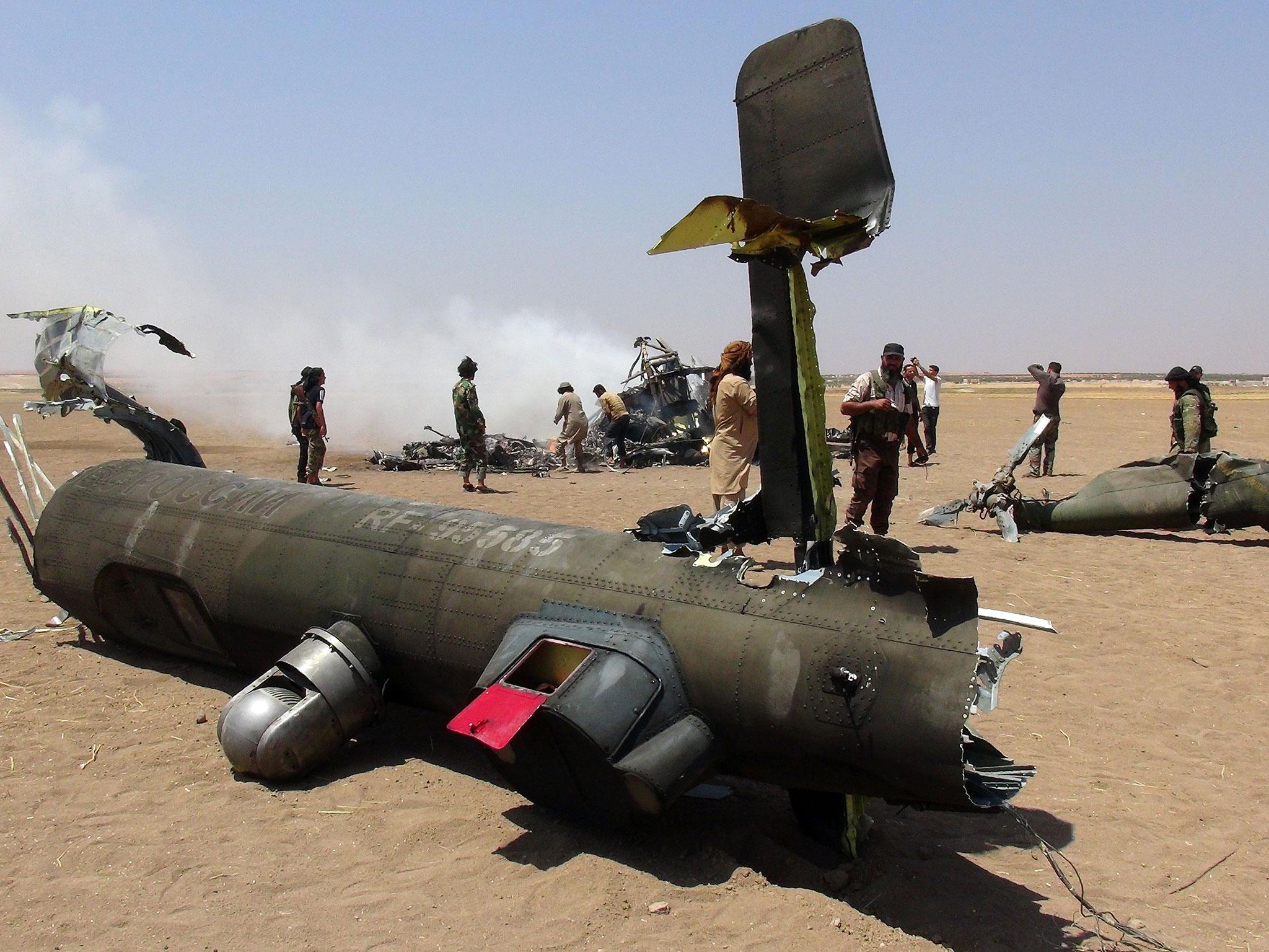 Syrian rebels gather around the wreckage of a Russian Mi-8 military transport helicopter after it was shot down along the administrative border between Idlib province, northwestern Syria and neighbouring Aleppo