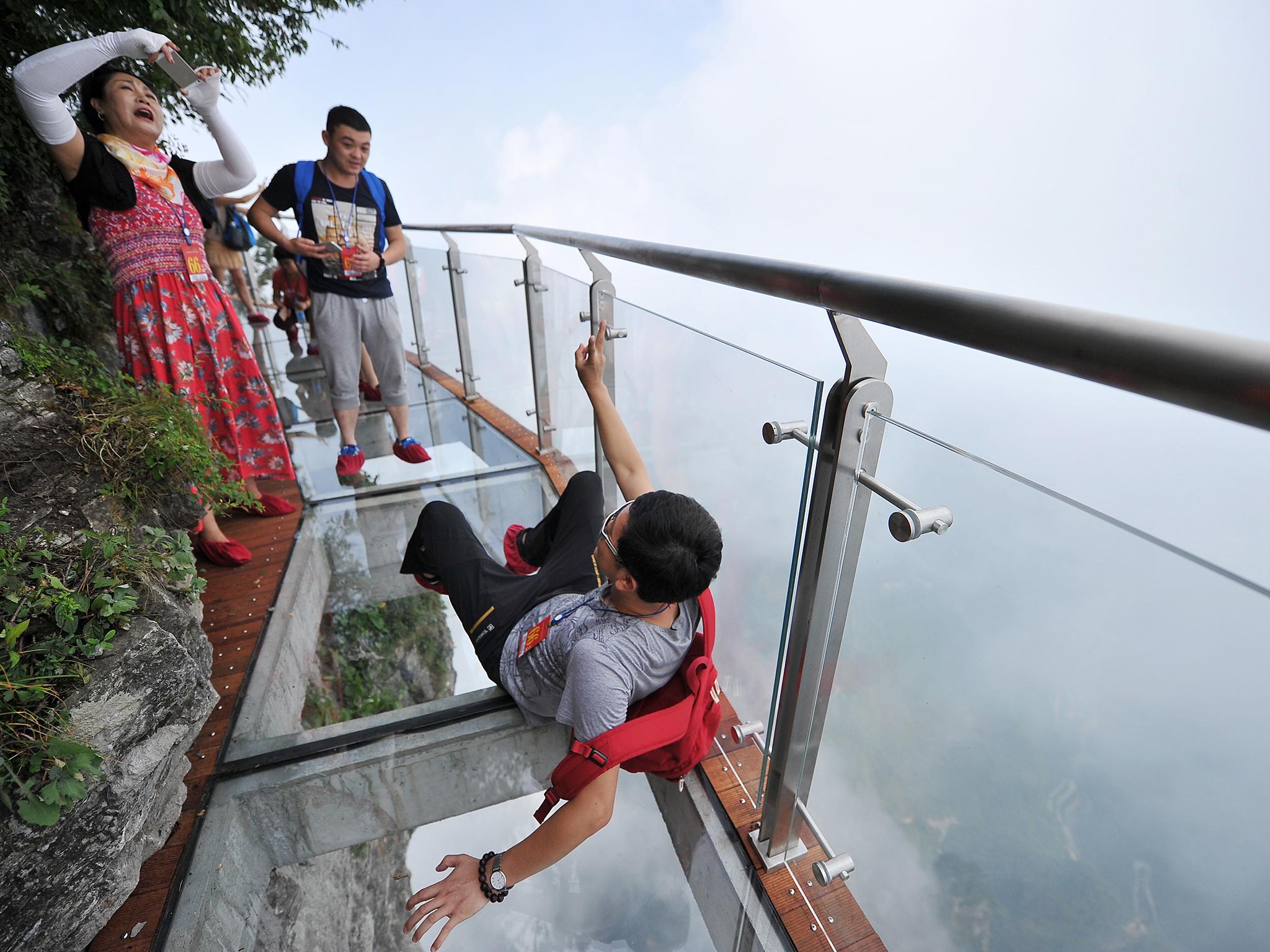 Tourists walk on the 100-meter-long and 1.6-meter-wide glass skywalk clung the cliff of Tianmen Mountain (or Tianmenshan Mountain) in Zhangjiajie National Forest Park