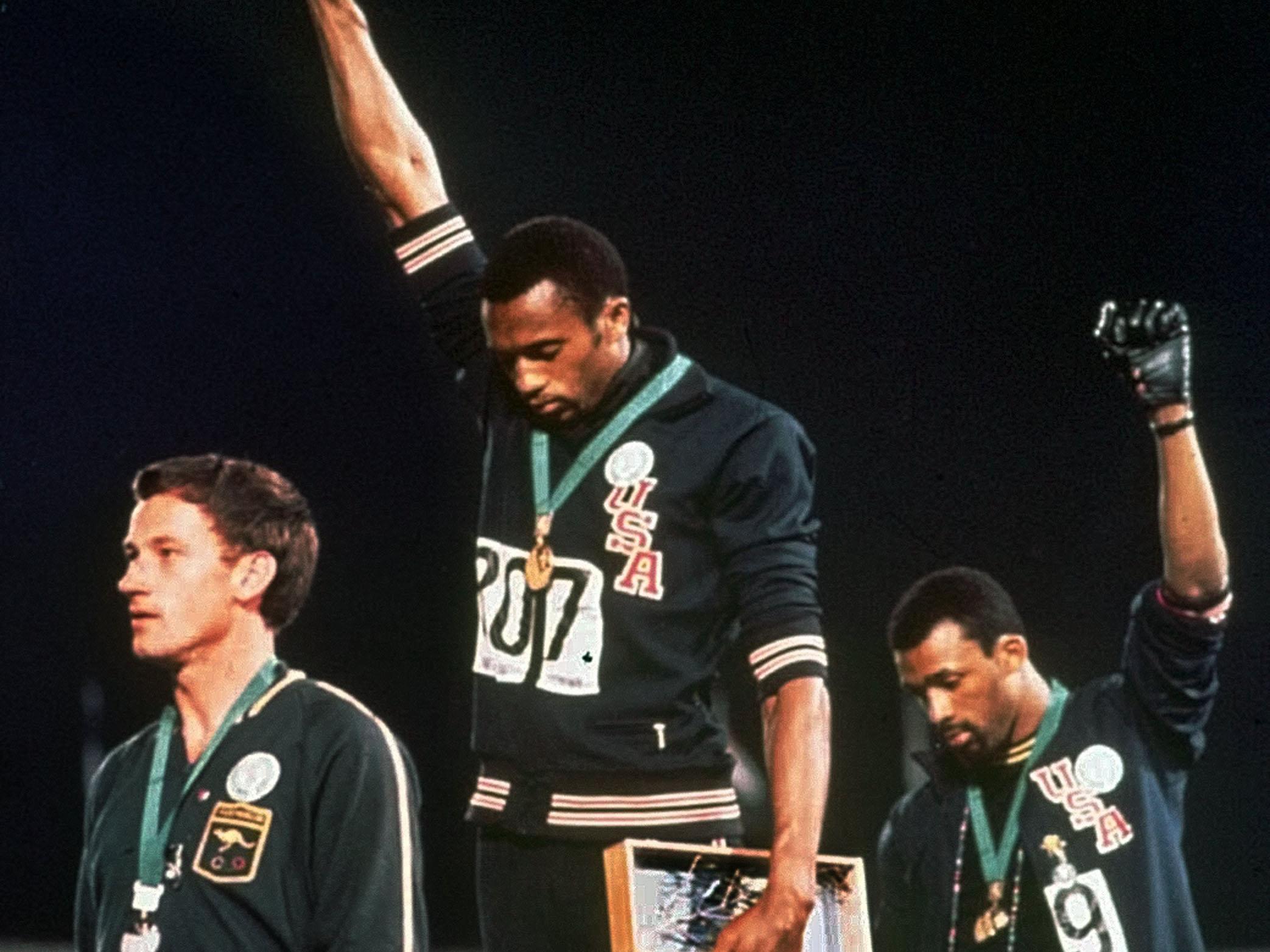 Gold medallist Tommie Smith and bronze medalist John Carlos with raised fists on the podium after the 200 m race at the 1968 Summer Olympics; both wear Olympic Project for Human Rights badges. Peter Norman from Australia also wears an OPHR badge in solidarity to Smith and Carlos