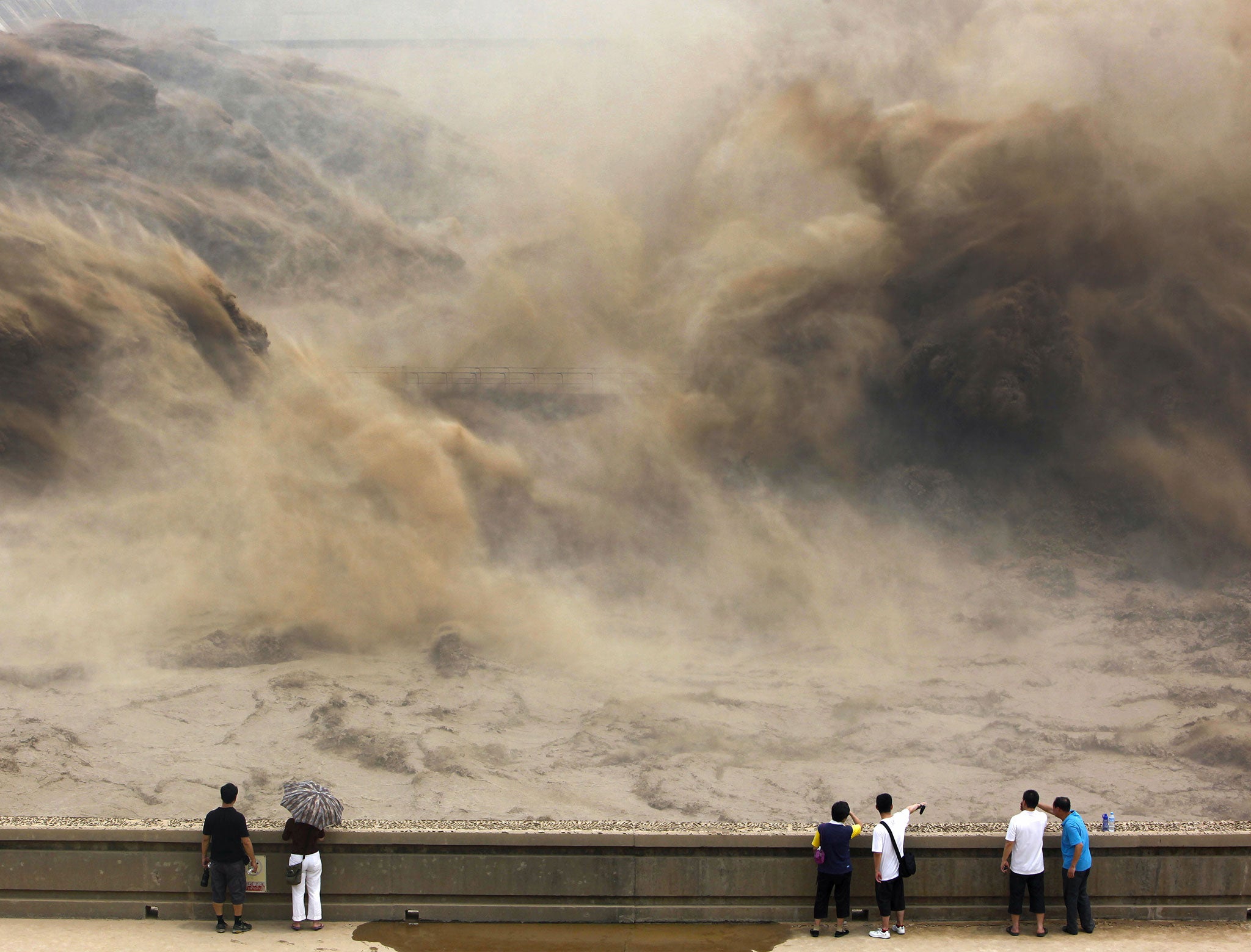 Visitors watch giant gushes of water released from the Xiaolangdi dam clearing up the sediment-laden Yellow river