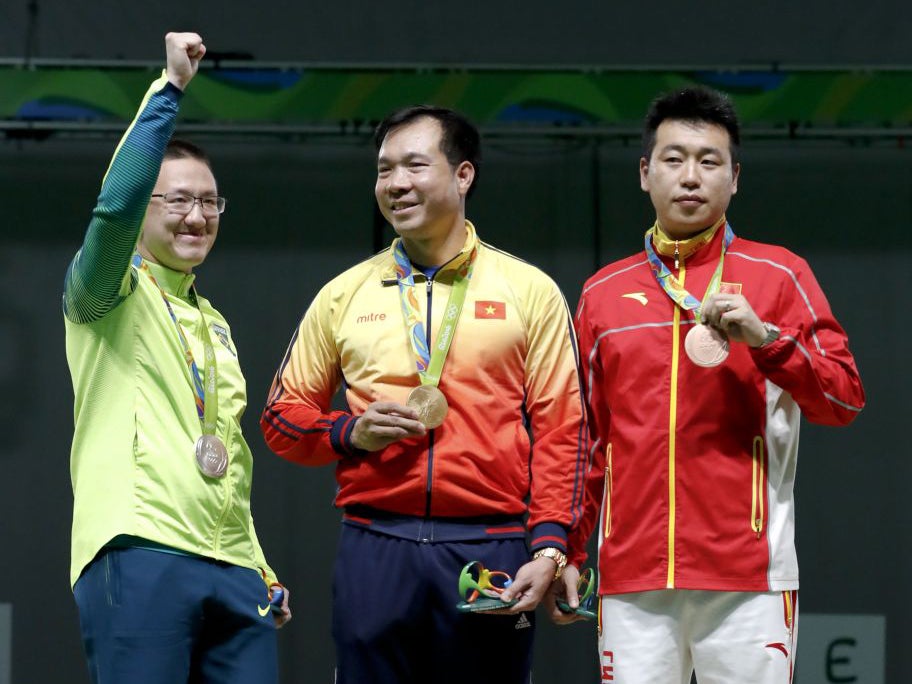 Gold medal winner, Hoang Xuan Vinh of Vietnam, center, silver medal winner, Felipe Almeida Wu of Brazil, left, and bronze medalist Pang Wei of China, at the victory ceremony for the men's 10-meter air pistol event