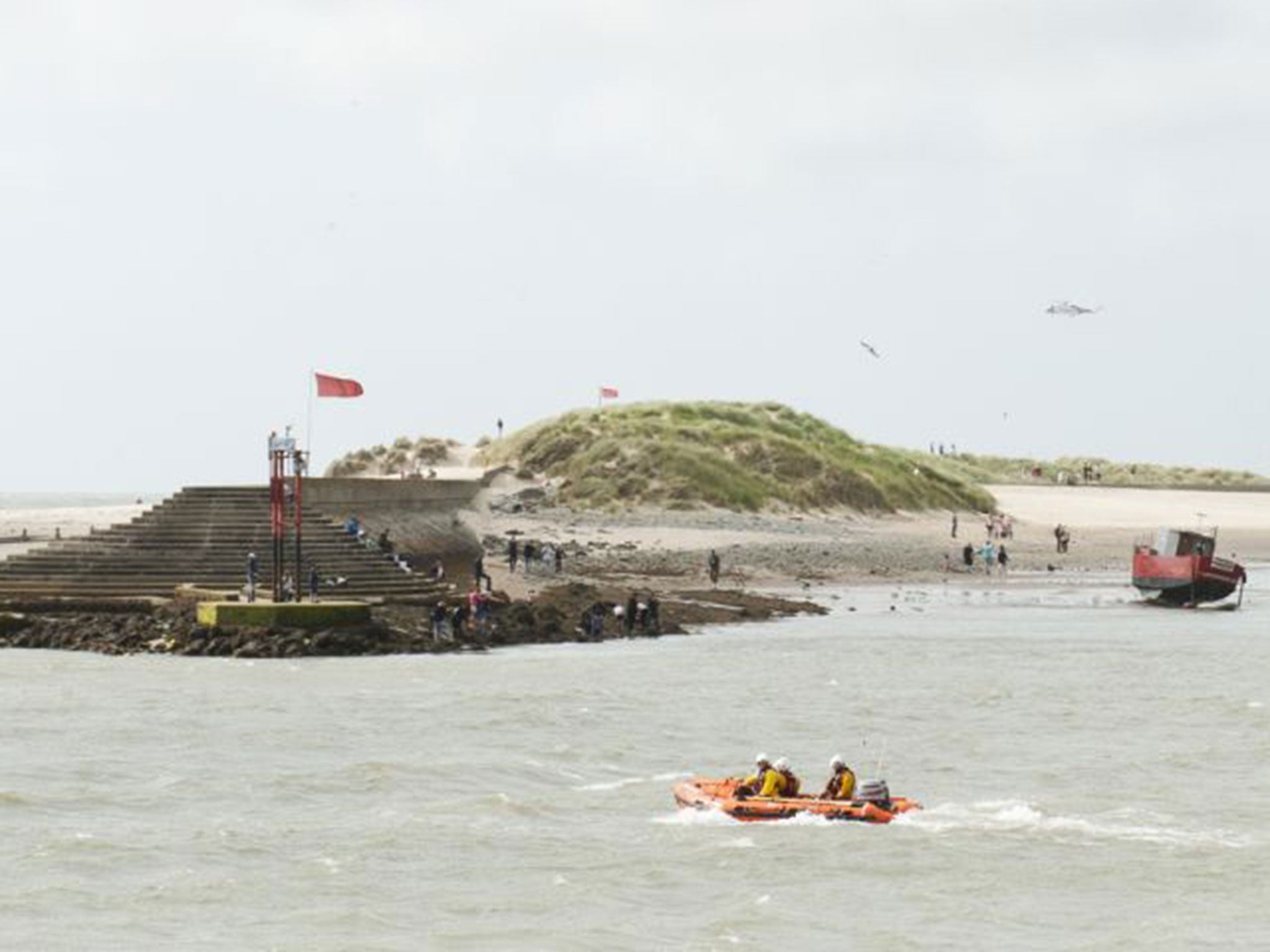 A RNLI lifeboat and a rescue helicopter search Barmouth Beach where two boys are missing in the sea