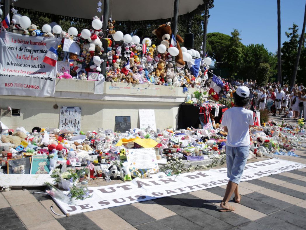 A boy walks by the make shift memorial as people dressed in white attend a minute of silence held for the victims of the Bastille Day attack