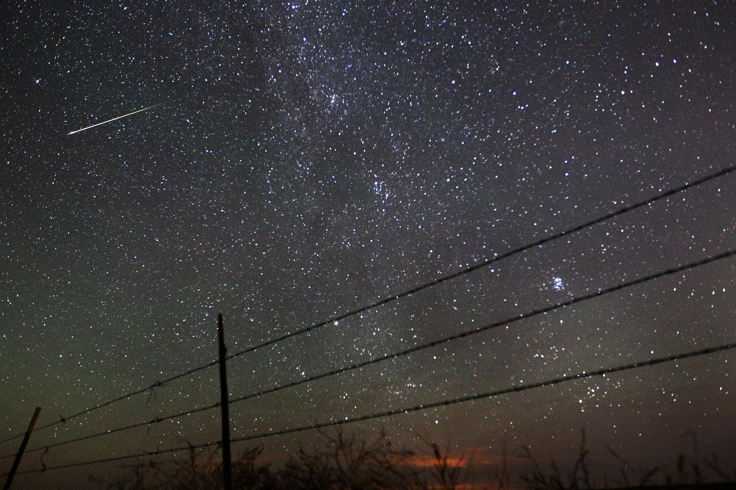 A meteor streaks past the faint band of the Milky Way galaxy above the Wyoming countryside north of Cheyenne during a Perseids meteor shower.