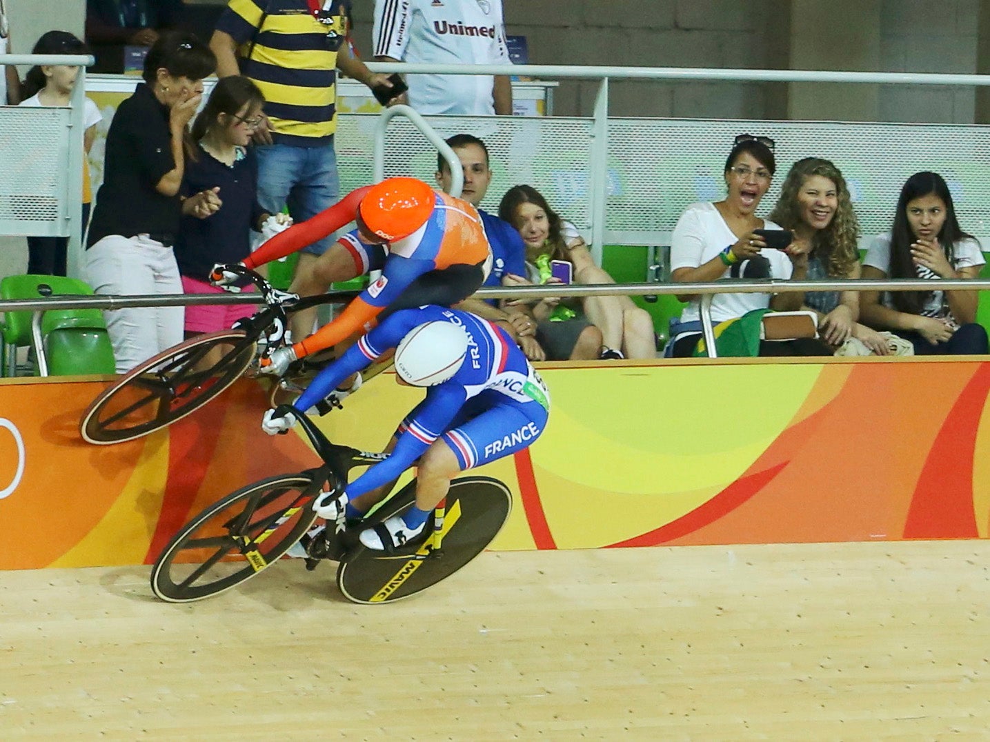 Laurine van Riessen of the Netherlands (in orange) avoids a crash with Virginie Cueff of France (in blue) during the women's keirin first round cycling track event