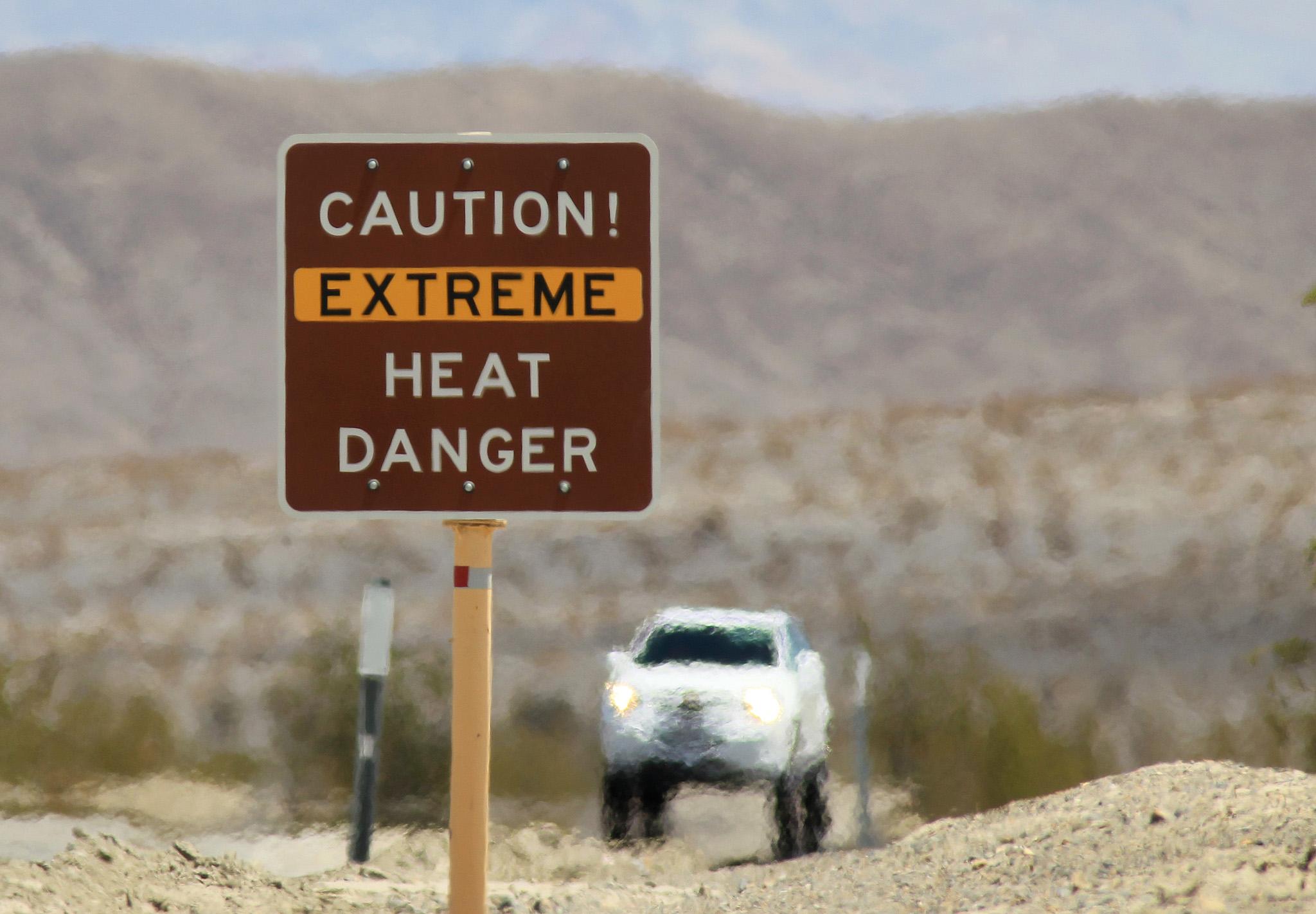 Heat waves rise near a heat danger warning sign on the eve of the AdventurCORPS Badwater 135 ultra-marathon race on July 14, 2013 in Death Valley National Park, California